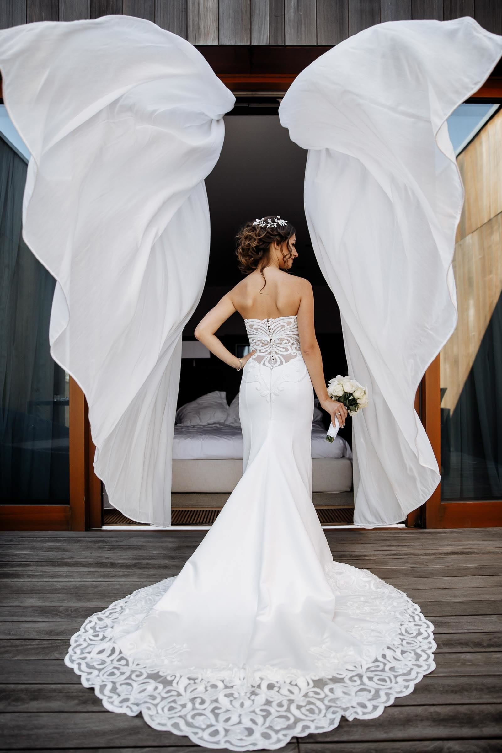 Classic editorial bridal portrait, with bride between curtains in the wind, by Tanya Bogdan Wedding Photography.