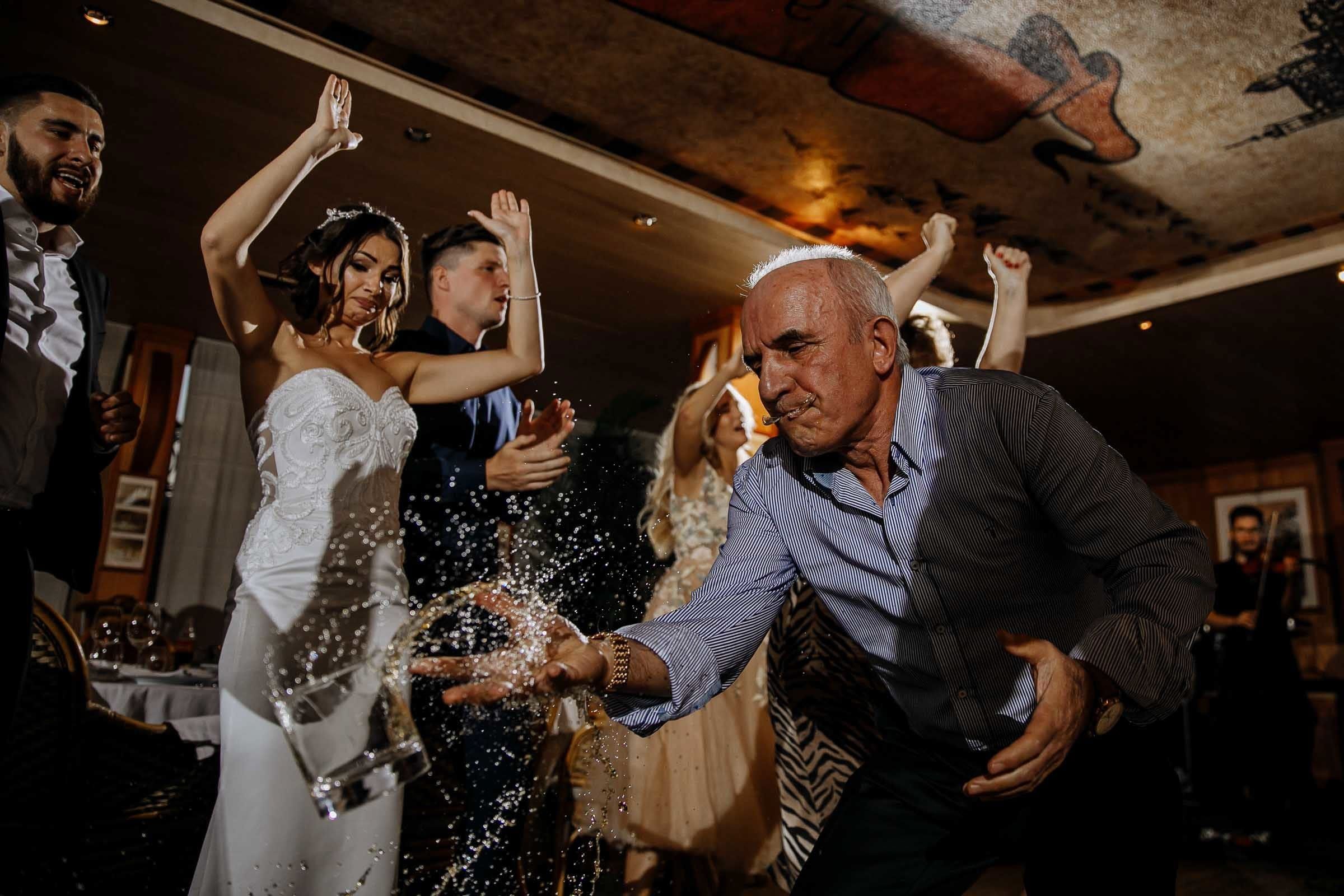Dramatic documentary dancefloor moment of father spilling drink, as it flies through the air, by London wedding photographer Tanya Bogdan.