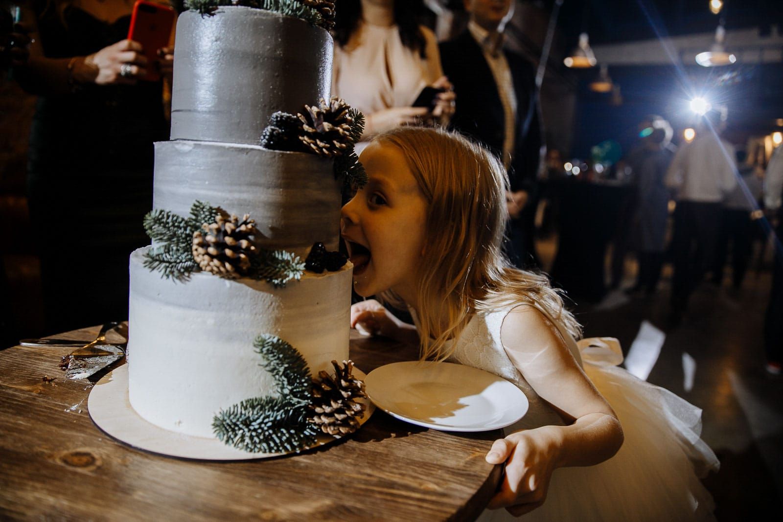 Playful photo of a girl by the wedding cake from Cornwall wedding photographer Tanya Bogdan.