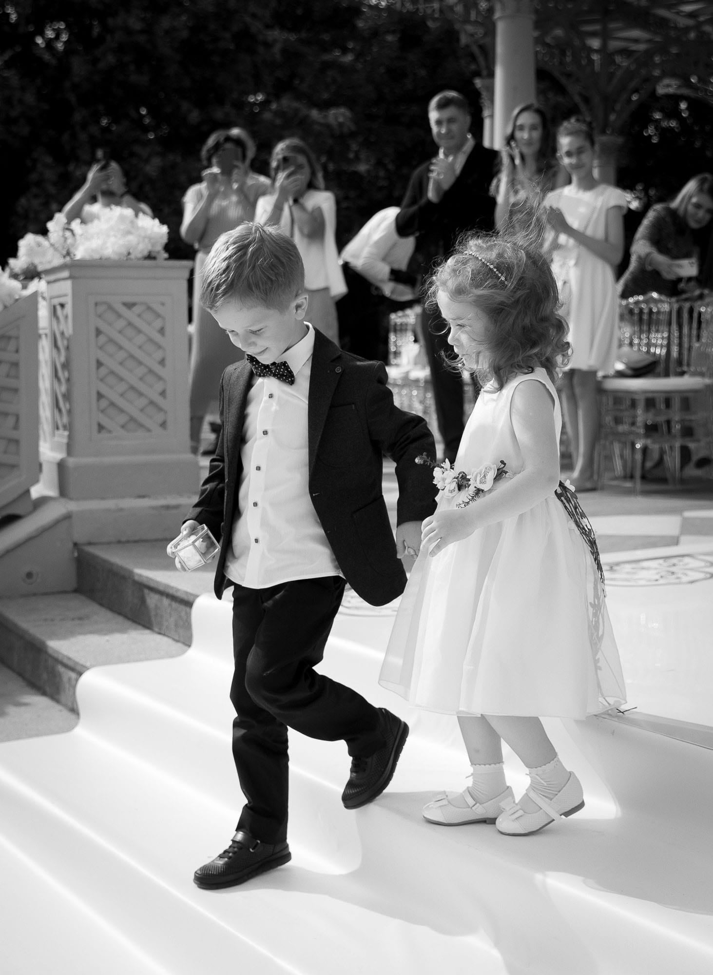 Flower girl and page boy walking together during a destination wedding ceremony