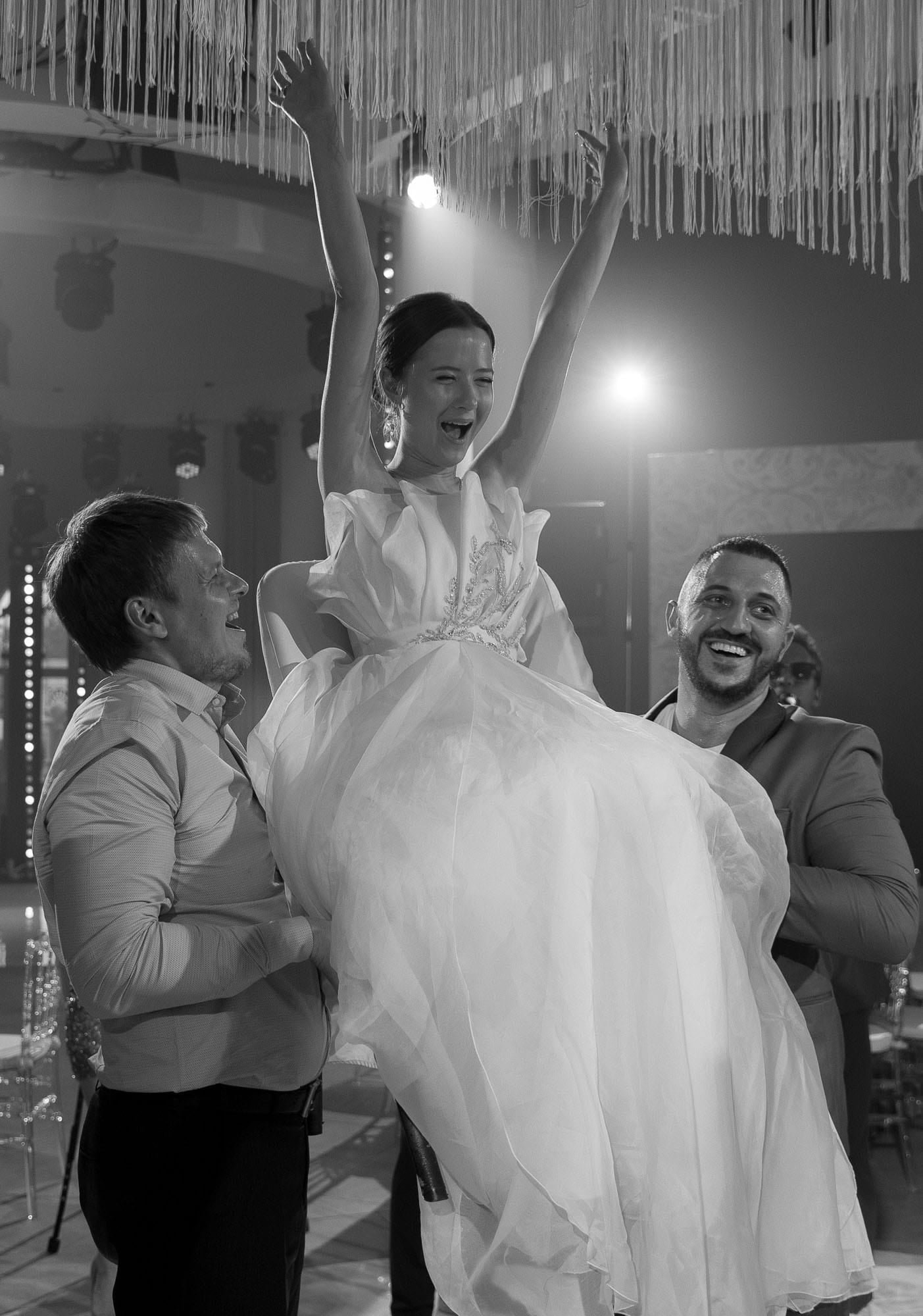 Bride lifted by friends during a joyful moment on the dancefloor at a destination wedding
