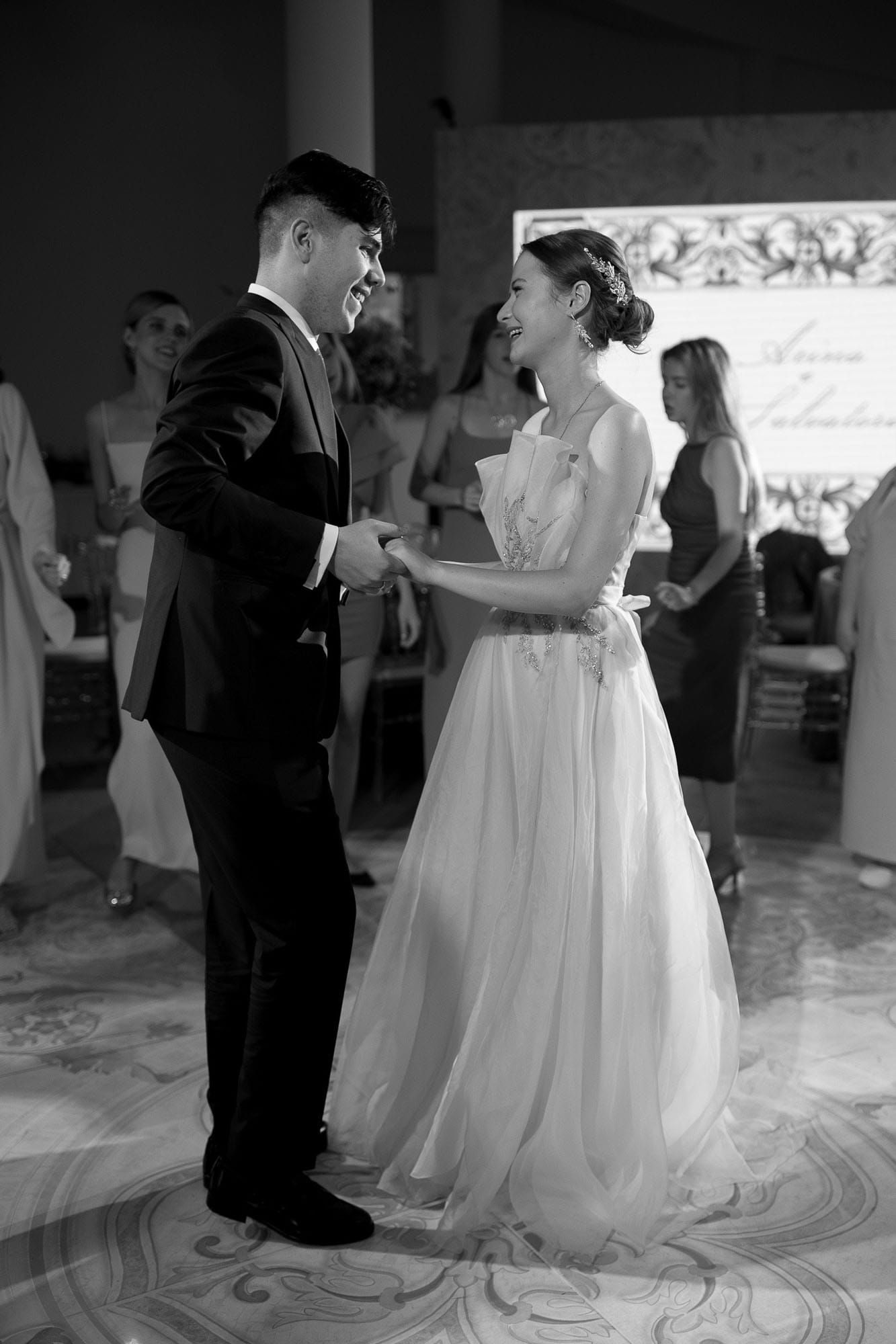 Black and white portrait of the bride and groom dancing together at their reception