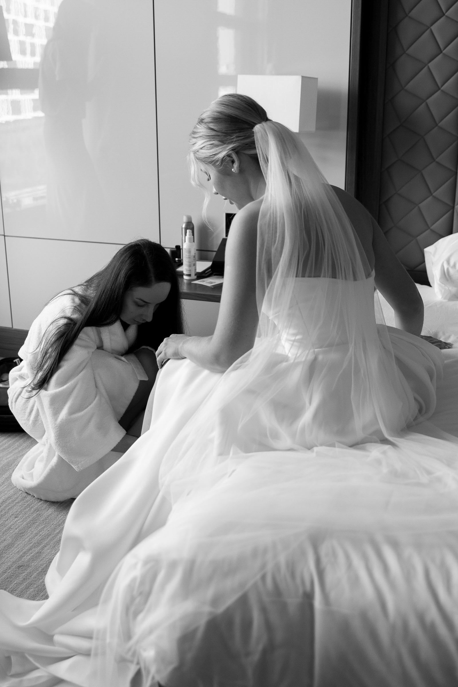Candid documentary moment of bridesmaid helping the bride with her shoes from Tanya Bogdan.