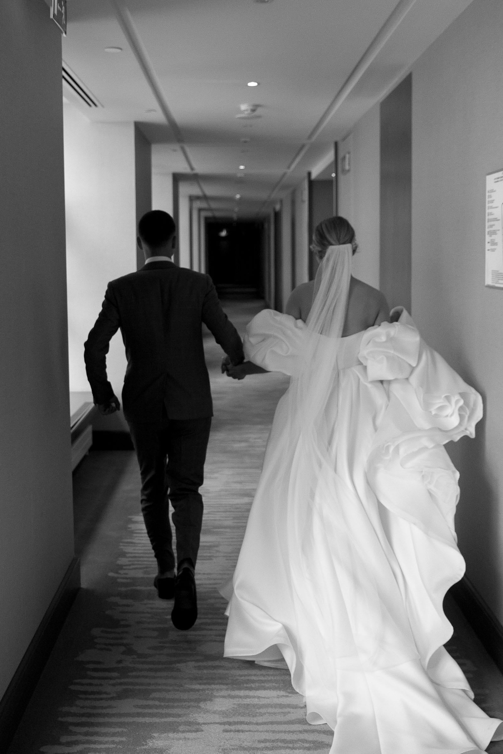 Candid documentary shot of a bride and groom running through a hallway from Devon wedding photographer Tanya Bogdan.