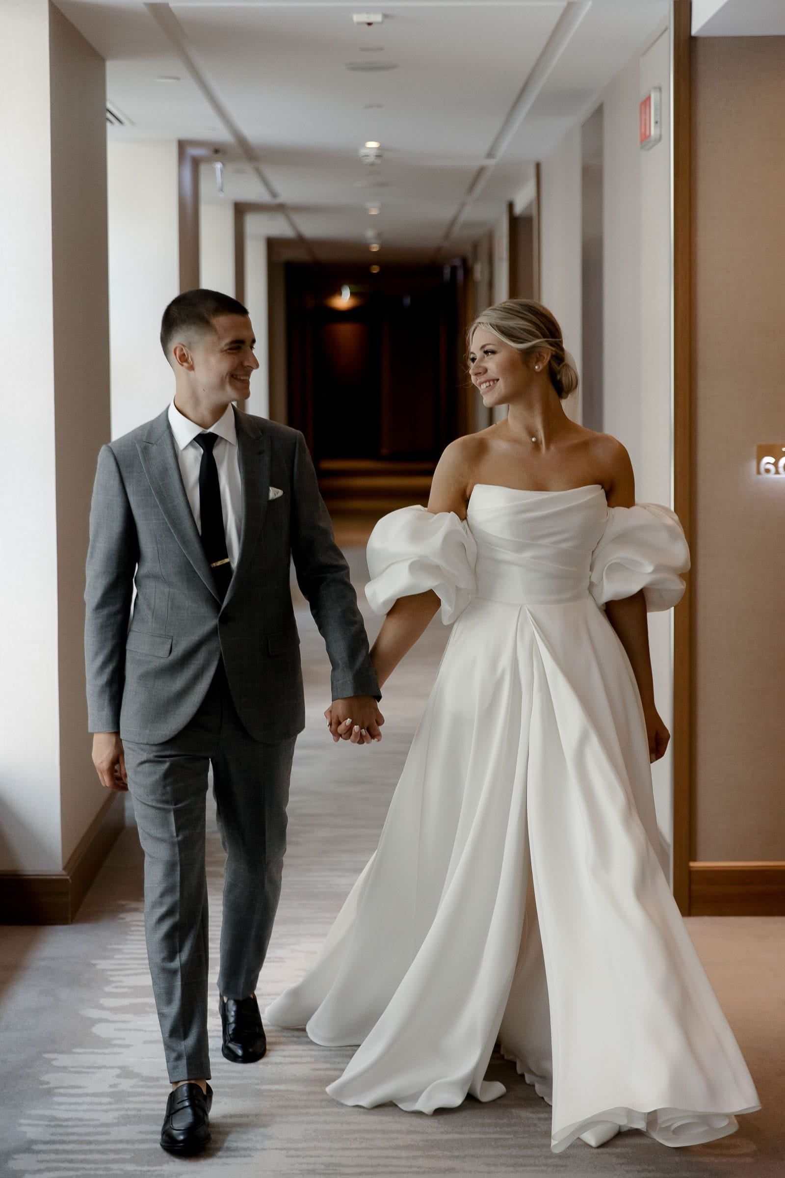 Candid indoor wedding photography of bride and groom holding hands from Devon wedding photographer Tanya Bogdan.