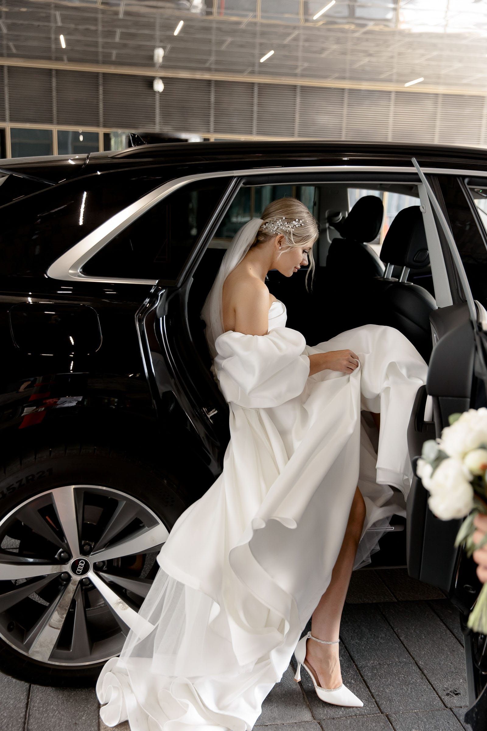 Documentary-style shot of a bride getting into a wedding car from Cornwall wedding photographer Tanya Bogdan.