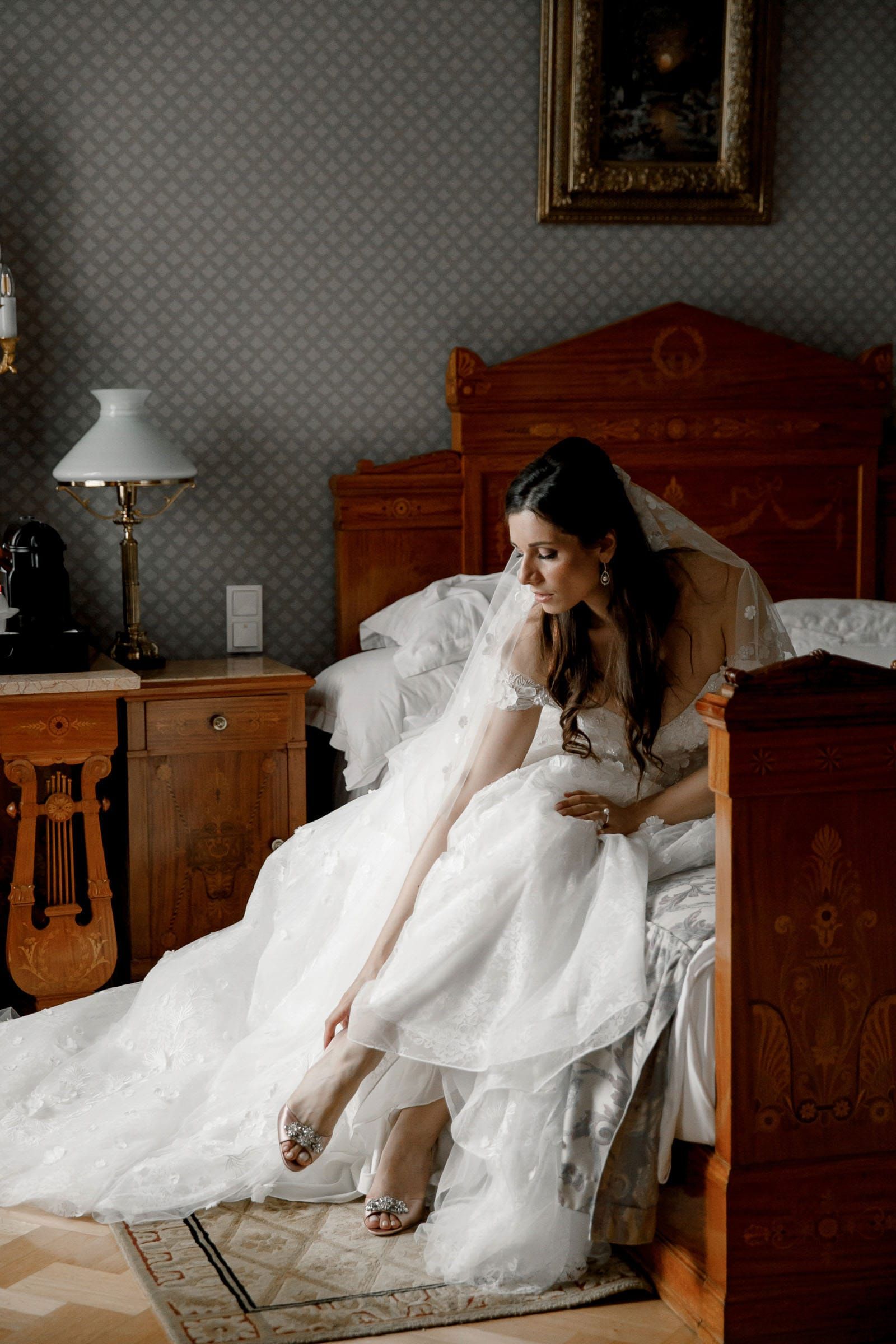 An editorial bridal portrait of bride putting on her shoes captured in soft natural light by Tanya Bogdan, serving Bude and the Cotswolds.