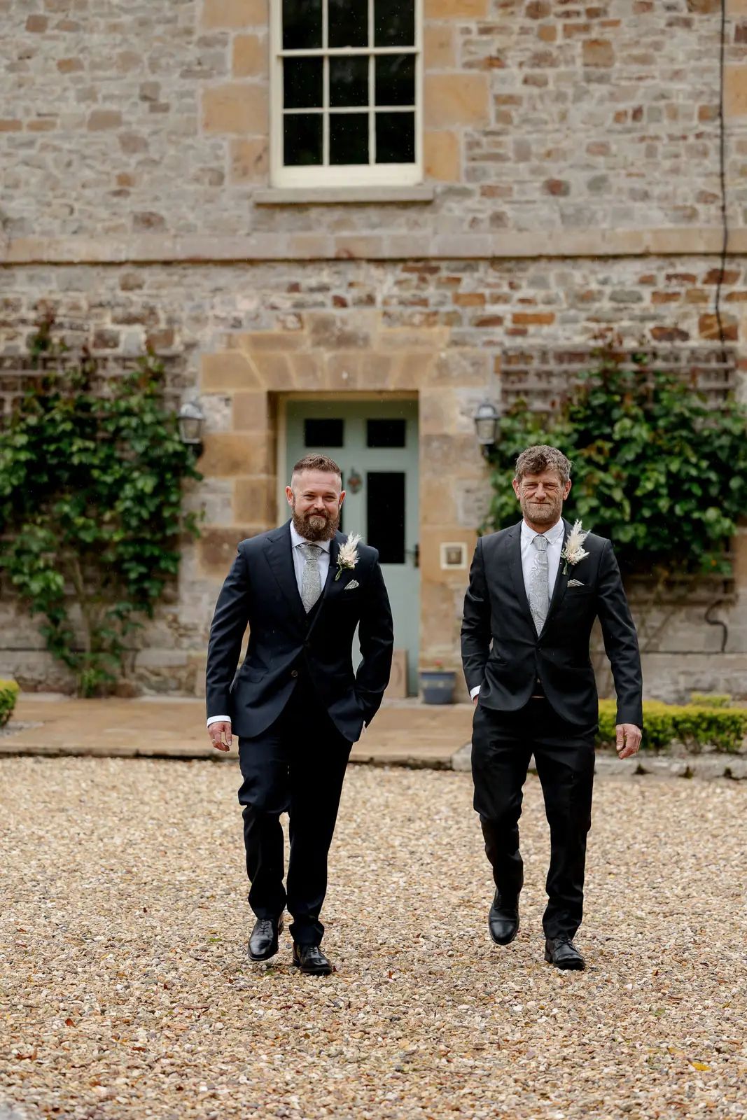 The groom and best man walk towards the wedding ceremony at Glebe Barn in Devon.