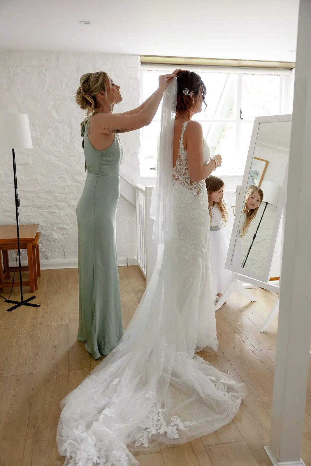 The bride gets ready with a bridesmaid before the wedding ceremony at Glebe Barn.