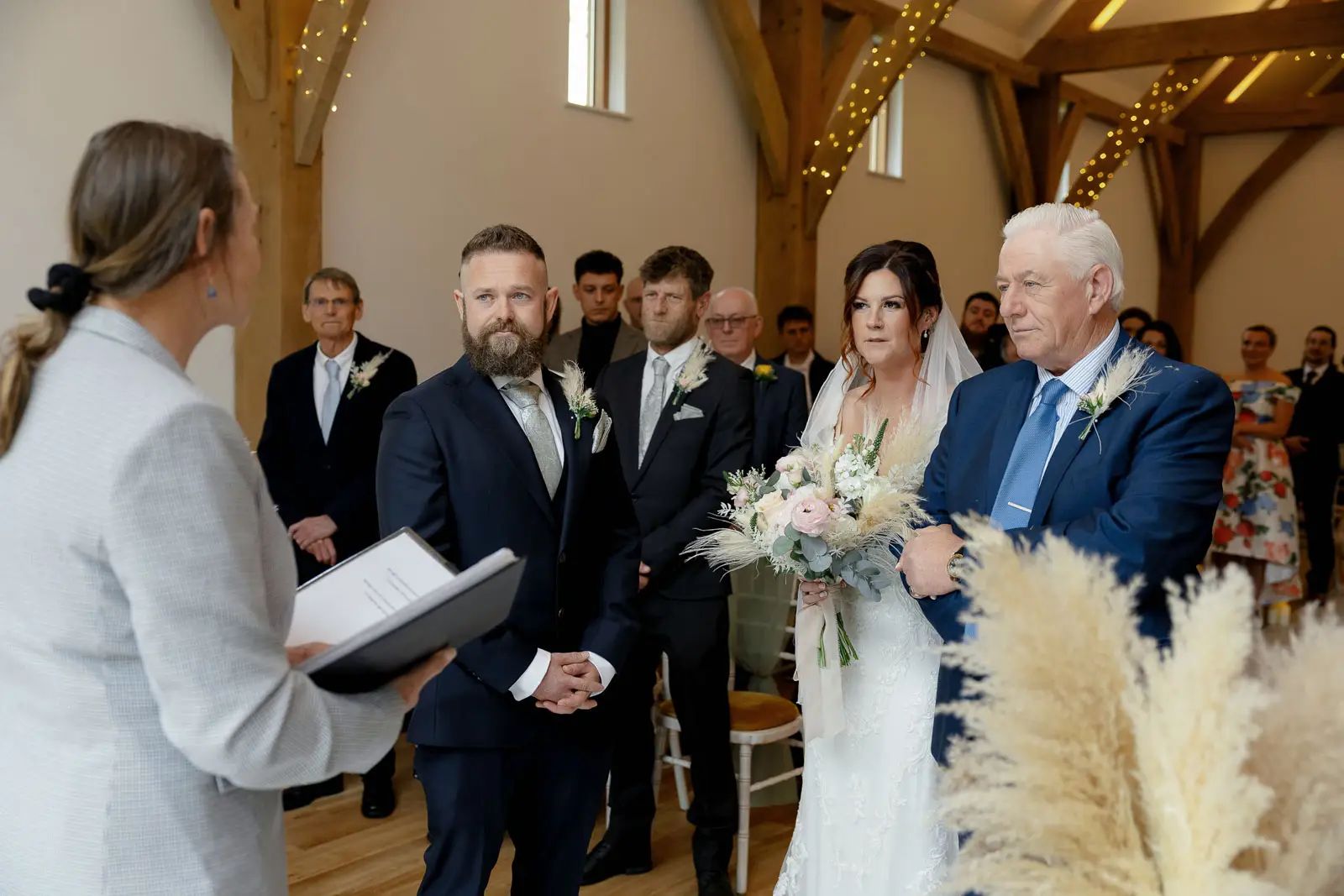 The bride and her father walk down the aisle during the wedding ceremony at Glebe Barn.