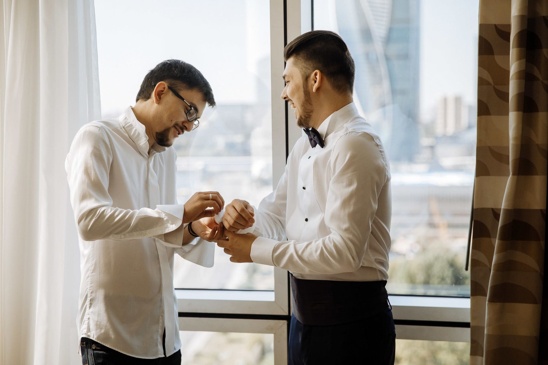 The best man helping the groom with his cufflinks, a candid preparation shot.