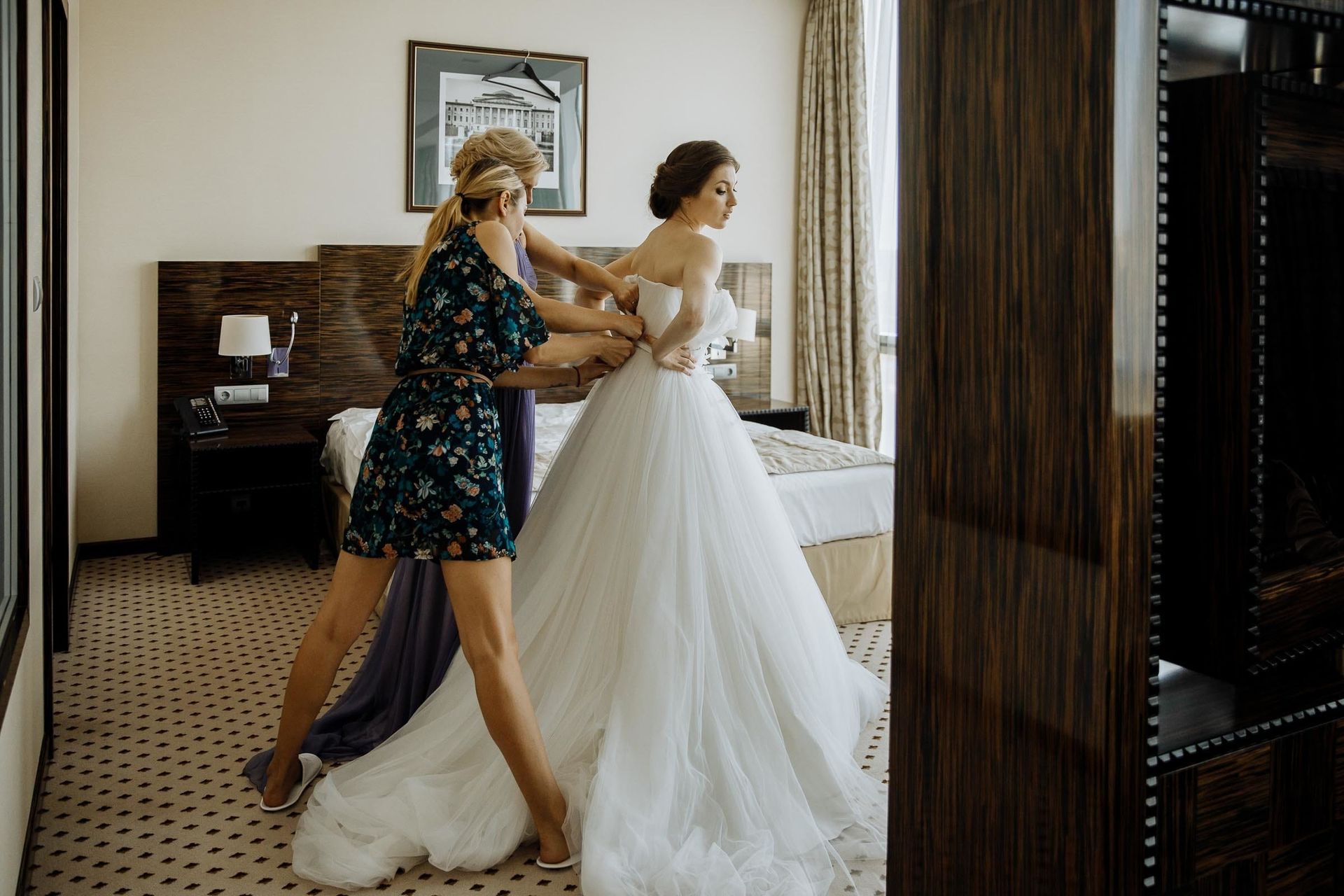 Candid shot of the bride being helped into her wedding dress by a bridesmaid.
