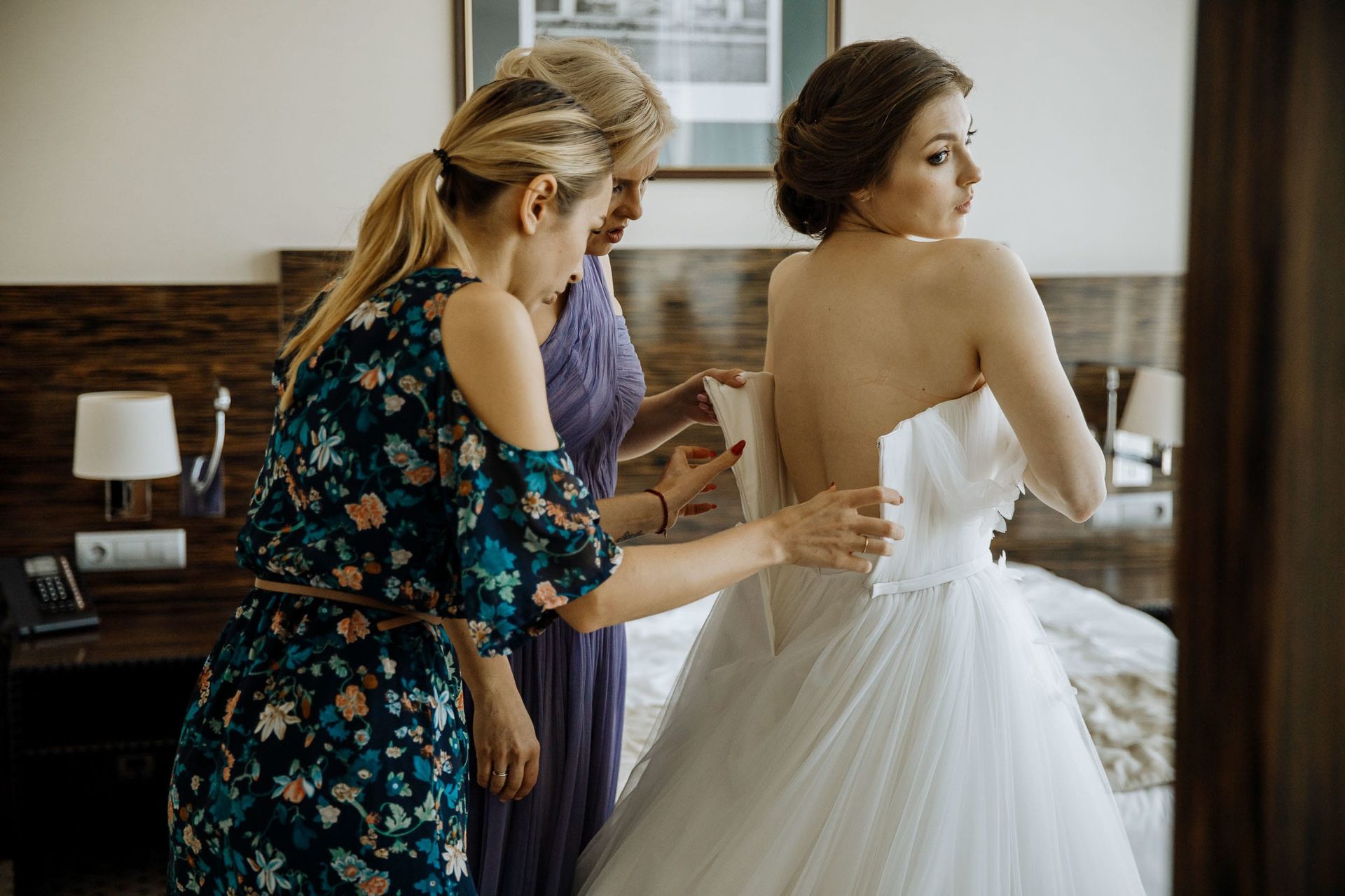 Close-up documentary photography of the bride’s dress being buttoned.