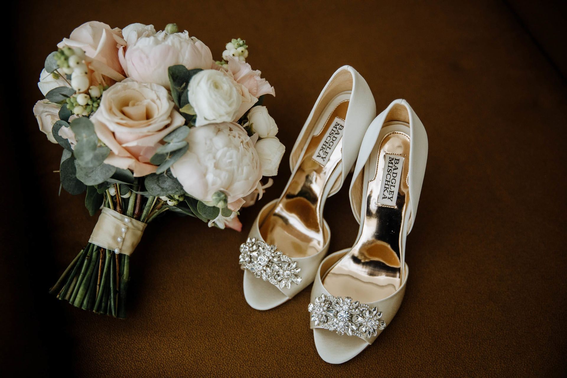 Fine art detail shot of the bridal bouquet, perfume, and wedding shoes.
