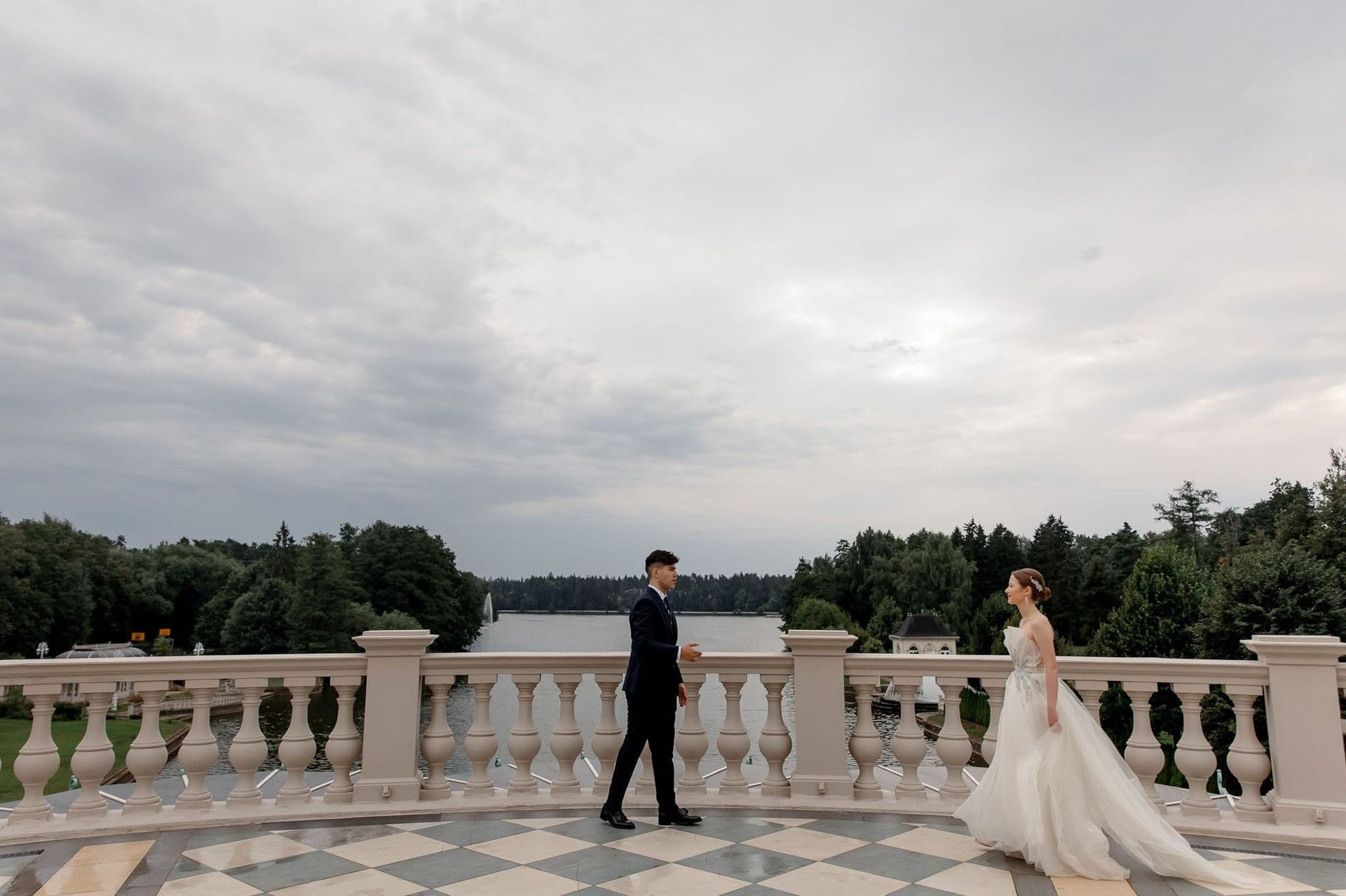 Bride walking toward the groom at a grand balcony overlooking a river at a destination wedding