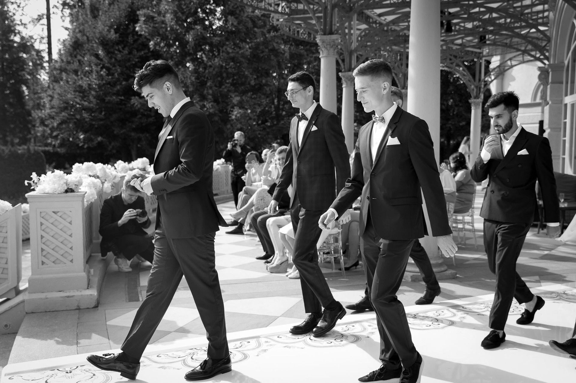 Black and white moment of groom and groomsmen walking during a destination wedding