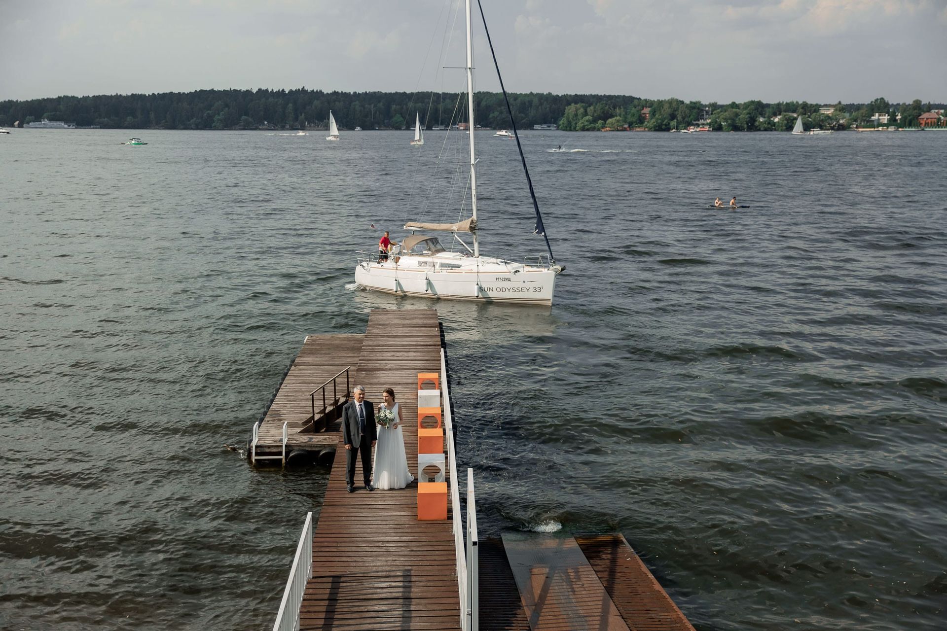 A father walking the bride across a harbour bridge, captured by Cornwall wedding photographer Tanya Bogdan.