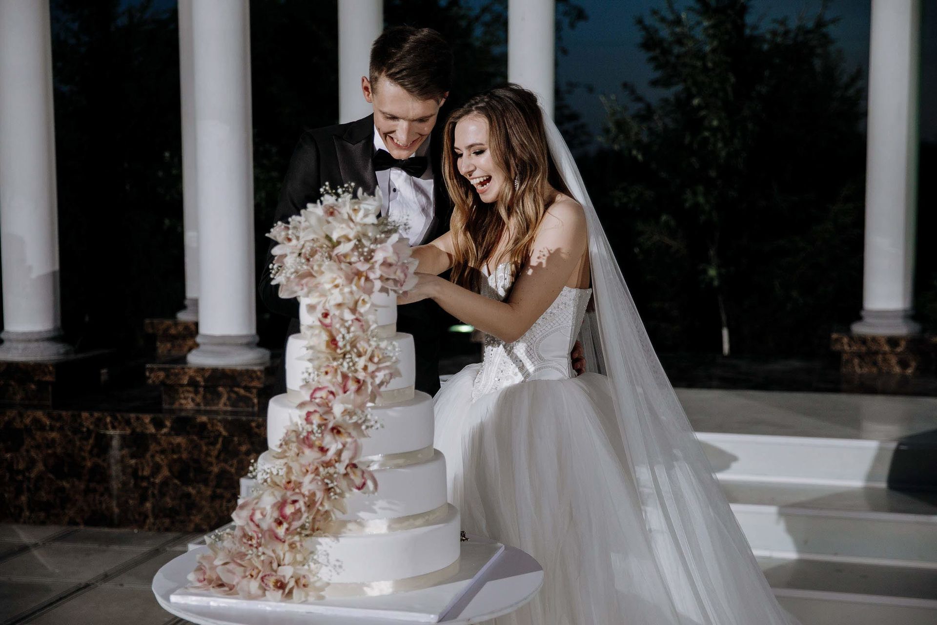 The bride and groom cutting their stylish wedding cake at their luxury reception.