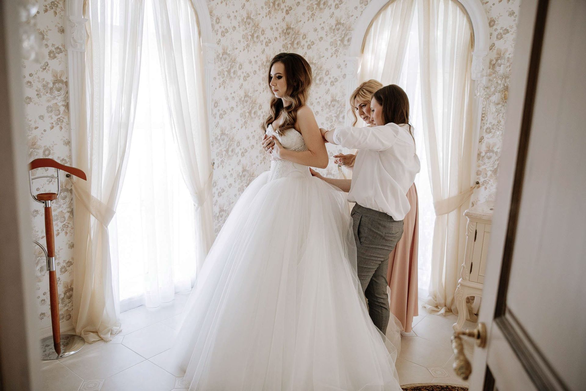 A heartfelt documentary moment showing the bride being helped into her gown by London photographer Tanya Bogdan.