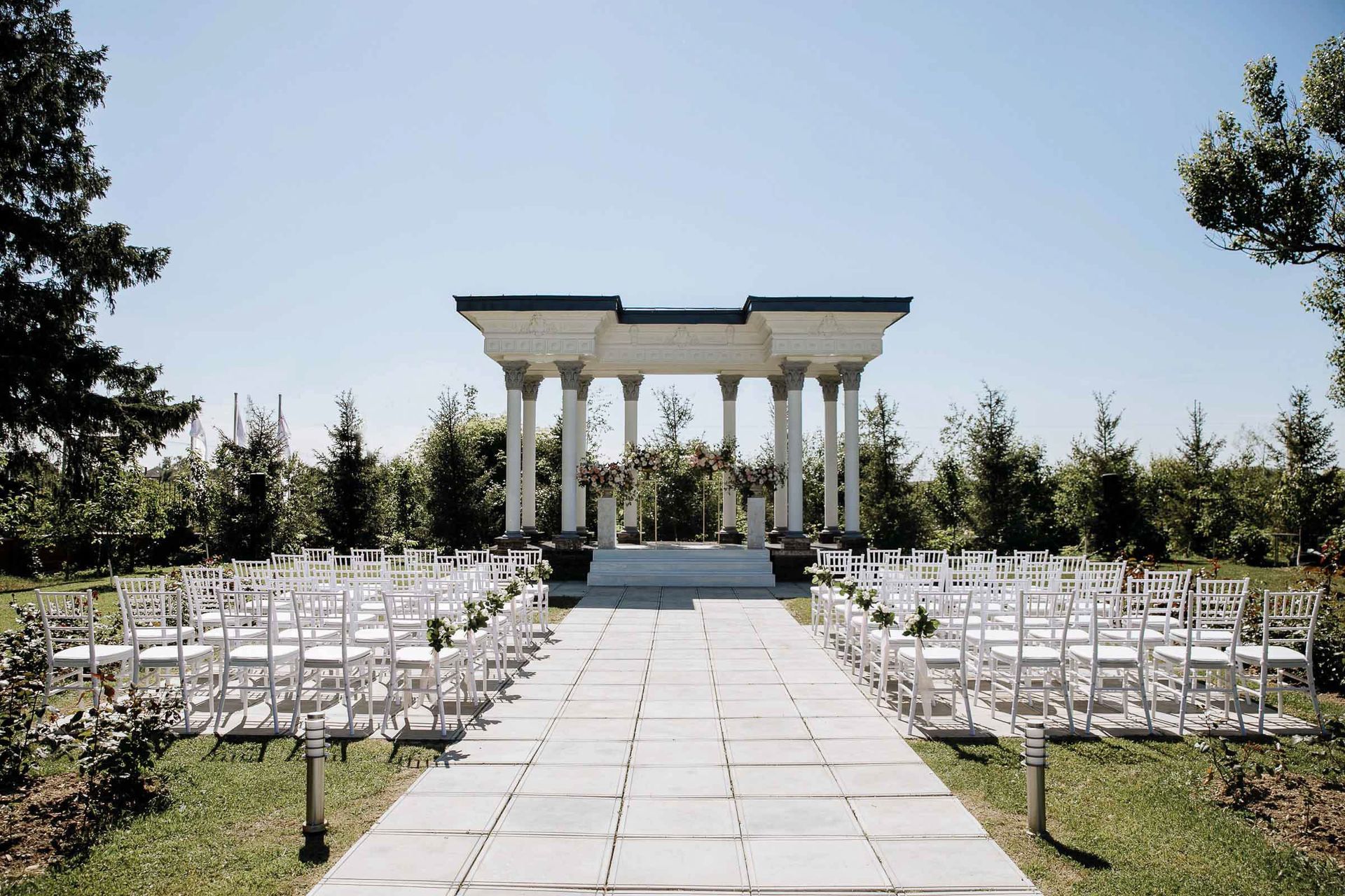 A wide editorial shot of an outdoor wedding ceremony featuring grand columns from London wedding photographer Tanya Bogdan.