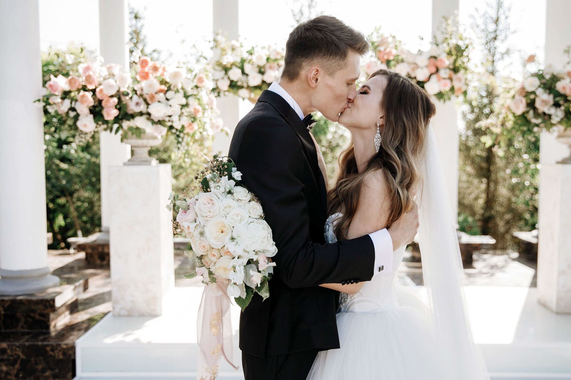 The romantic first kiss at a grand outdoor wedding, captured by Tanya Bogdan.