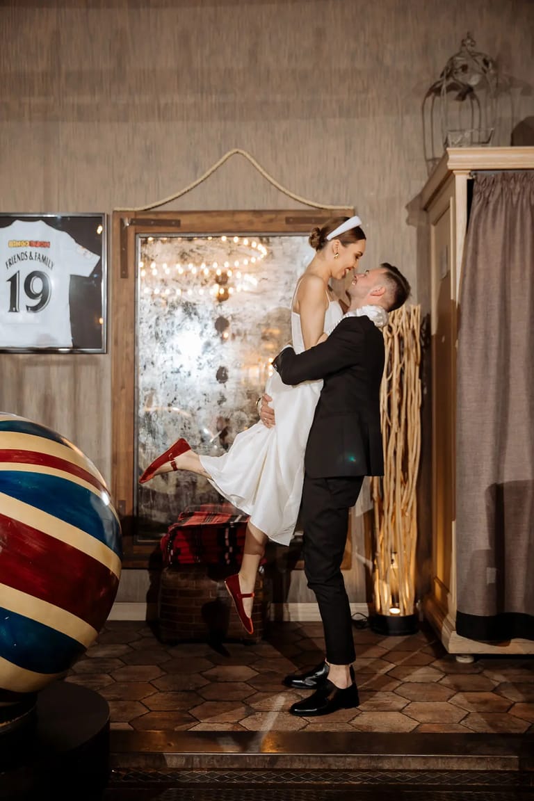 A playful and candid photo of a groom lifting his bride during a fun wedding moment, captured by Cornwall wedding photographer Tanya Bogdan.