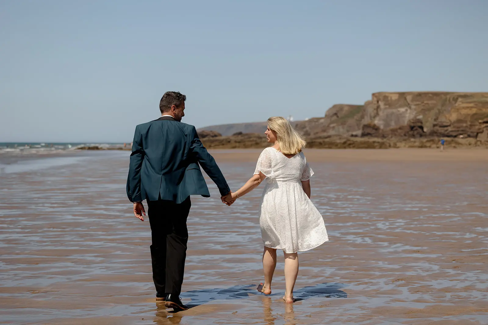 Bride and groom walking hand in hand on Summerleaze Beach in Bude, Cornwall