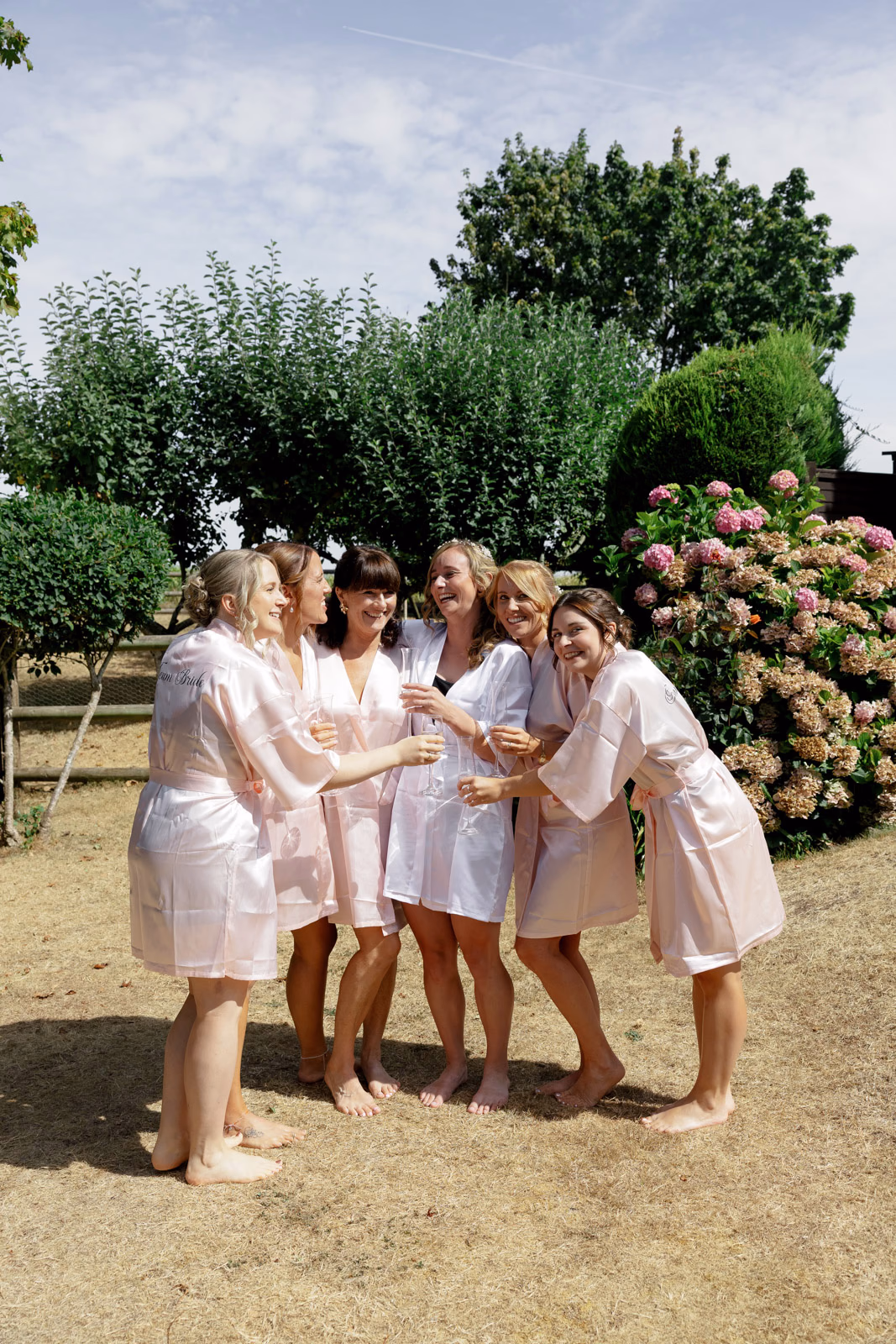 Bridesmaids in robes group hug garden at a countryside wedding in Taunton, Somerset