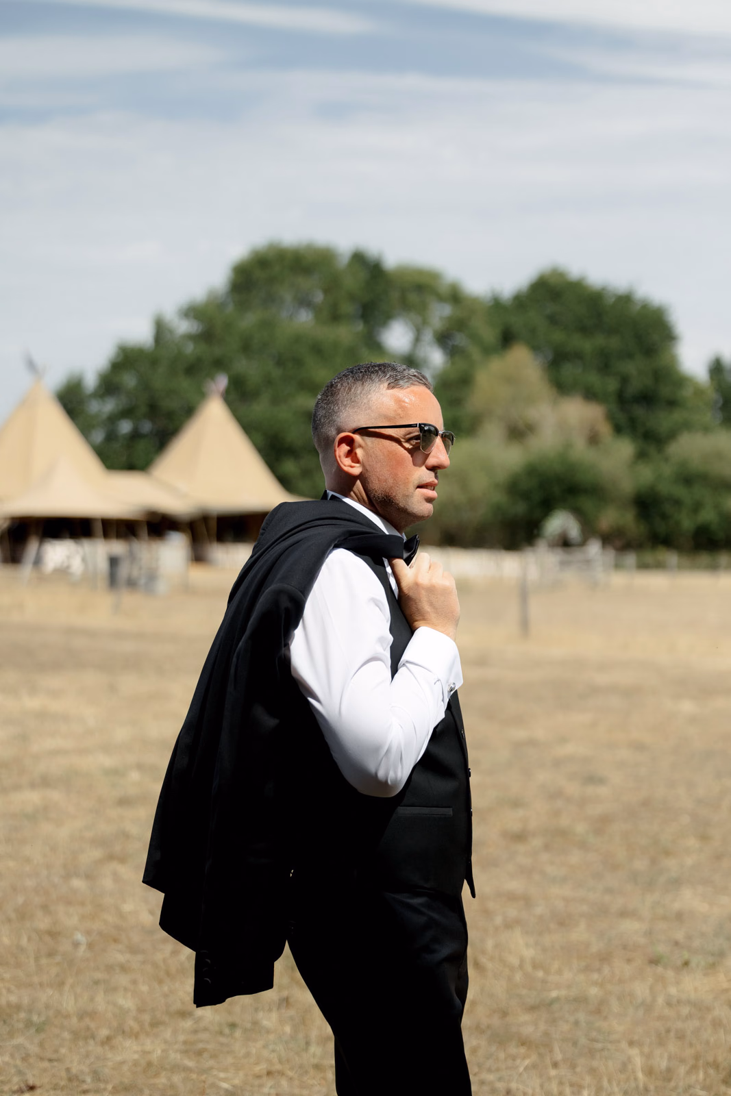 Groom portrait jacket over shoulder field at a family farm wedding in Taunton
