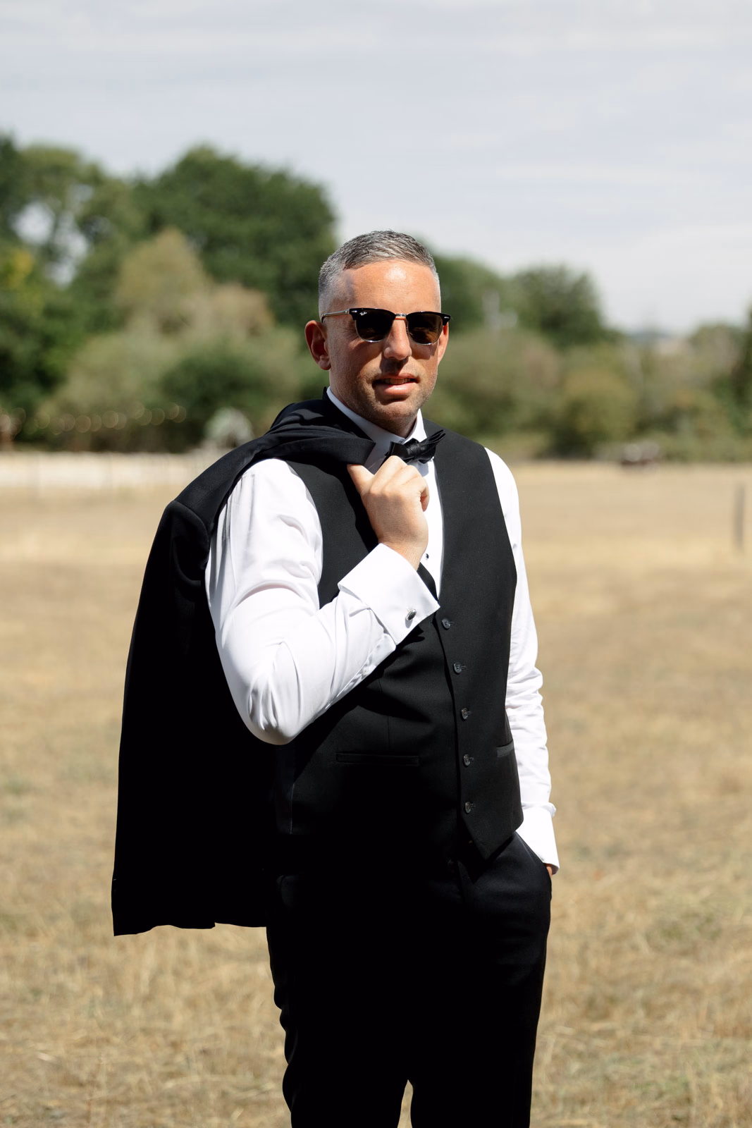Groom portrait sunglasses jacket over shoulder at a countryside wedding in Taunton, Somerset