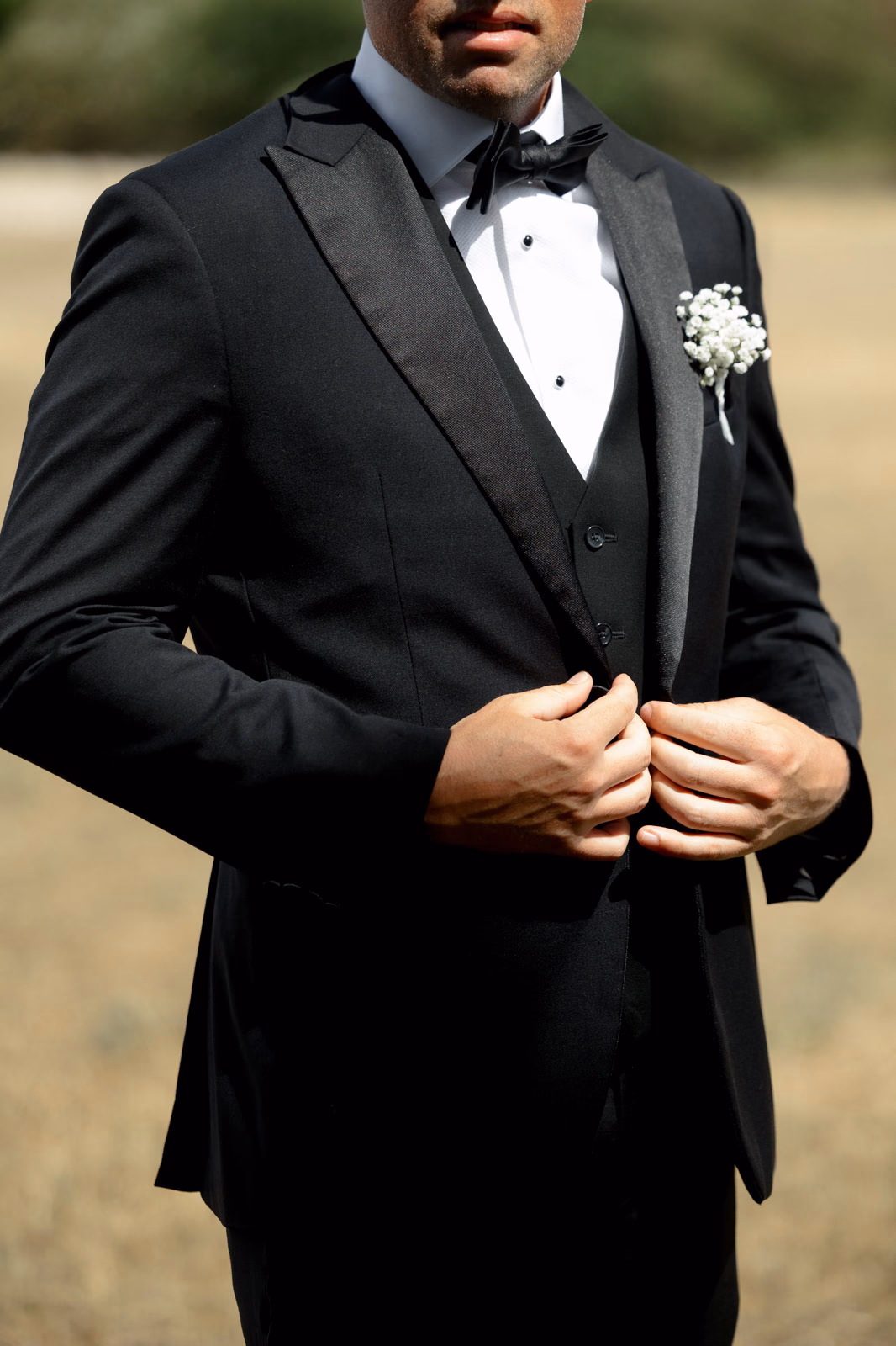 Groom suit detail buttoning jacket at a family farm wedding in Taunton