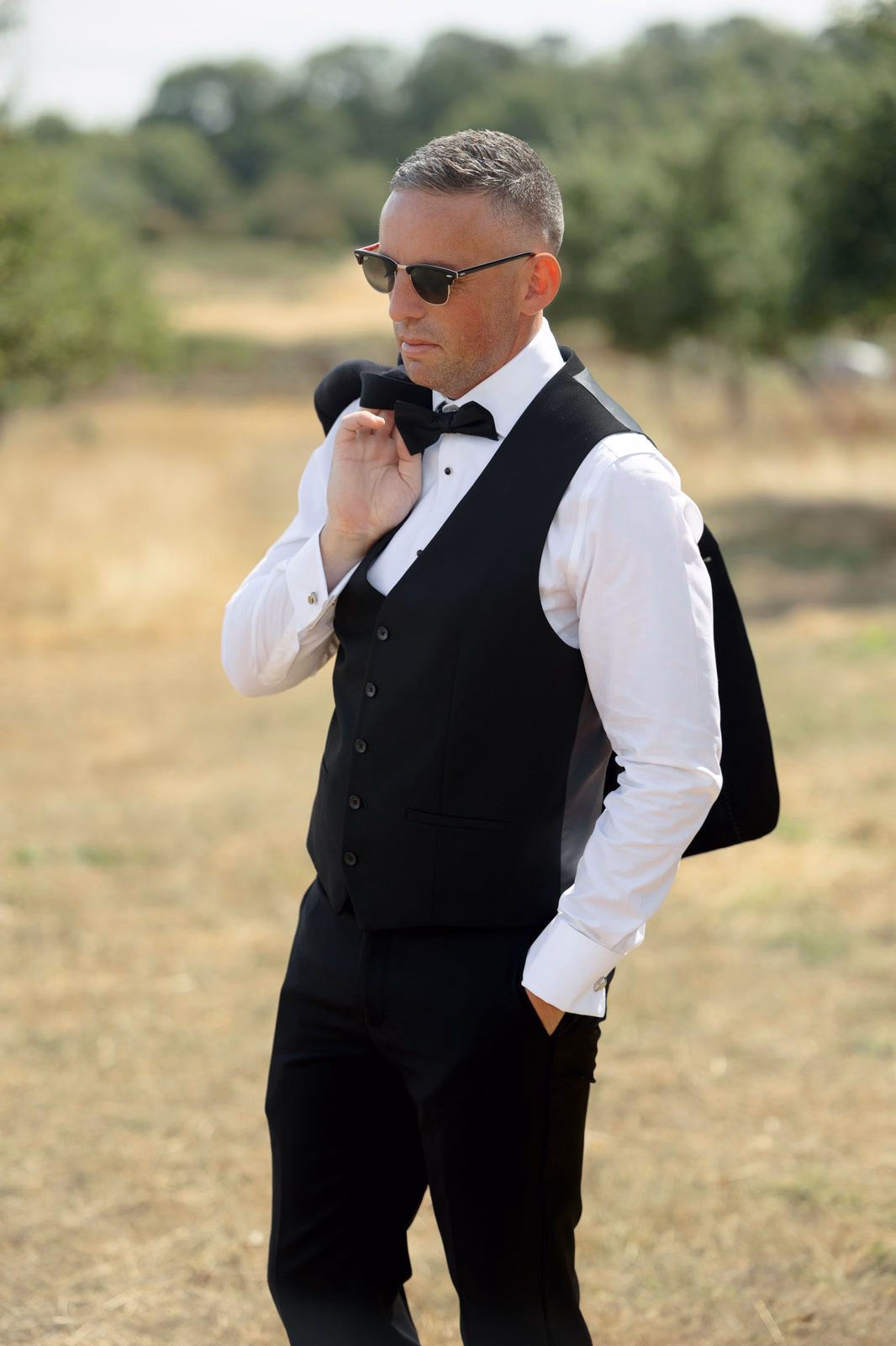 Groom portrait waistcoat jacket over shoulder at a Taunton farm wedding, photographed by Tanya Bogdan Photography
