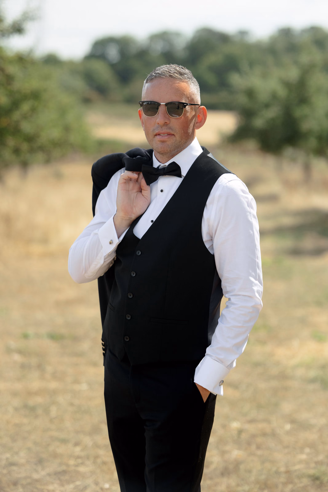 Groom portrait waistcoat relaxed pose at a family farm wedding in Taunton