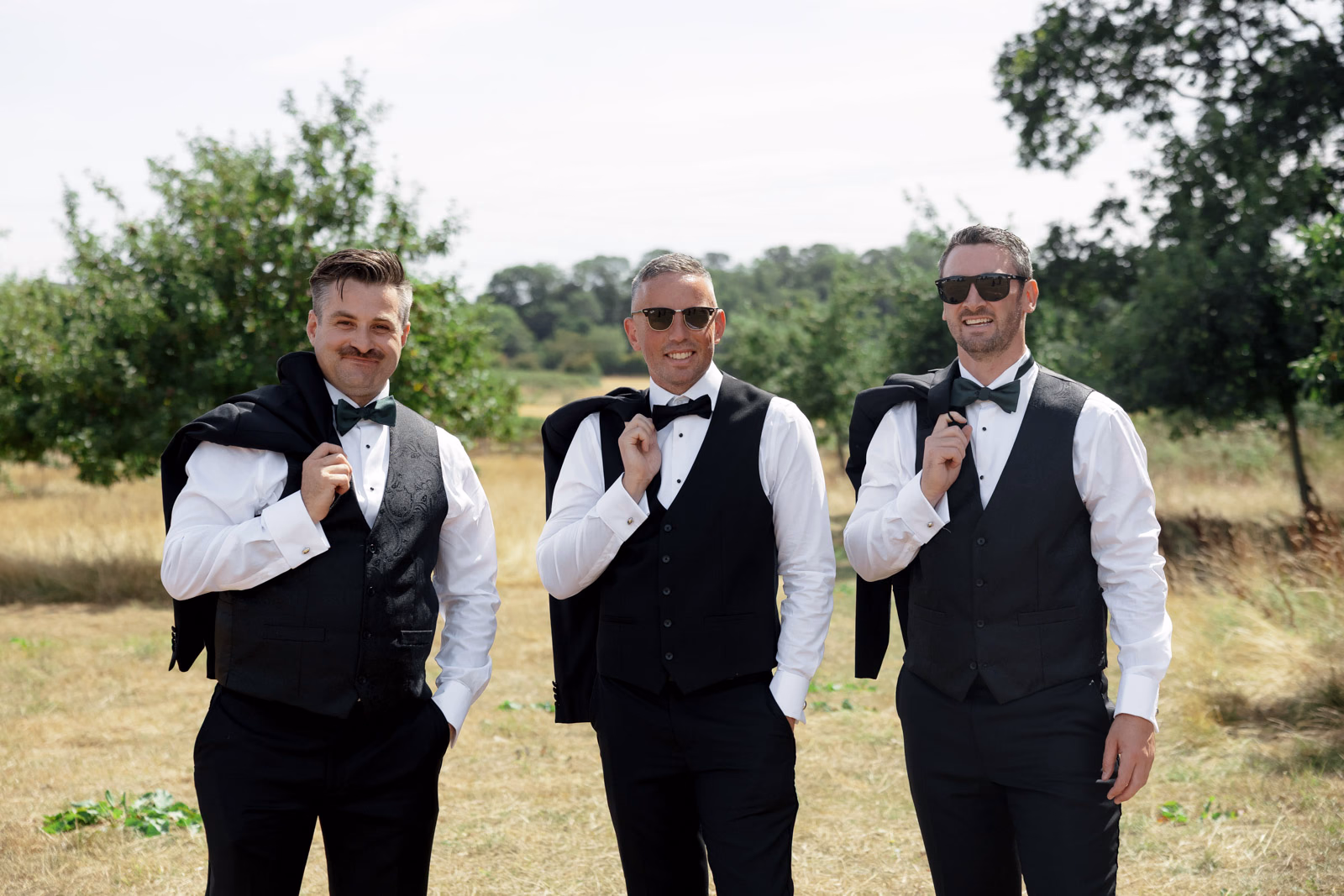 Groom and groomsmen waistcoats jackets over shoulders at a countryside wedding in Taunton, Somerset