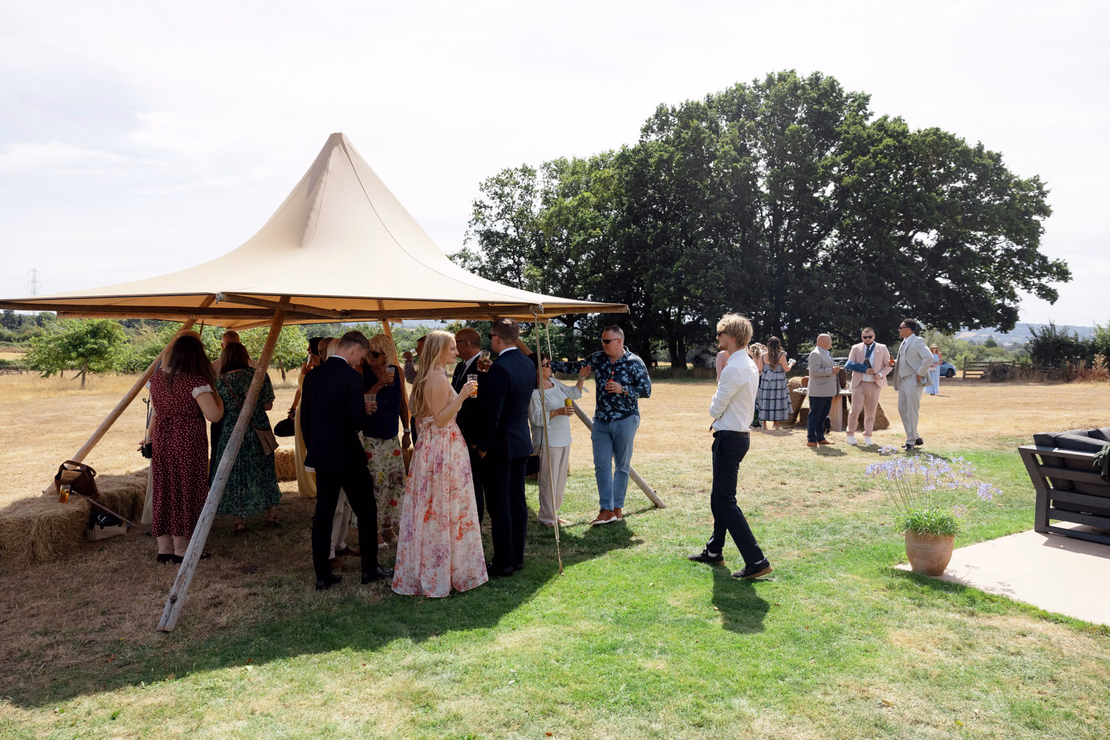 Guests chatting welcome drinks tipi at a family farm wedding in Taunton
