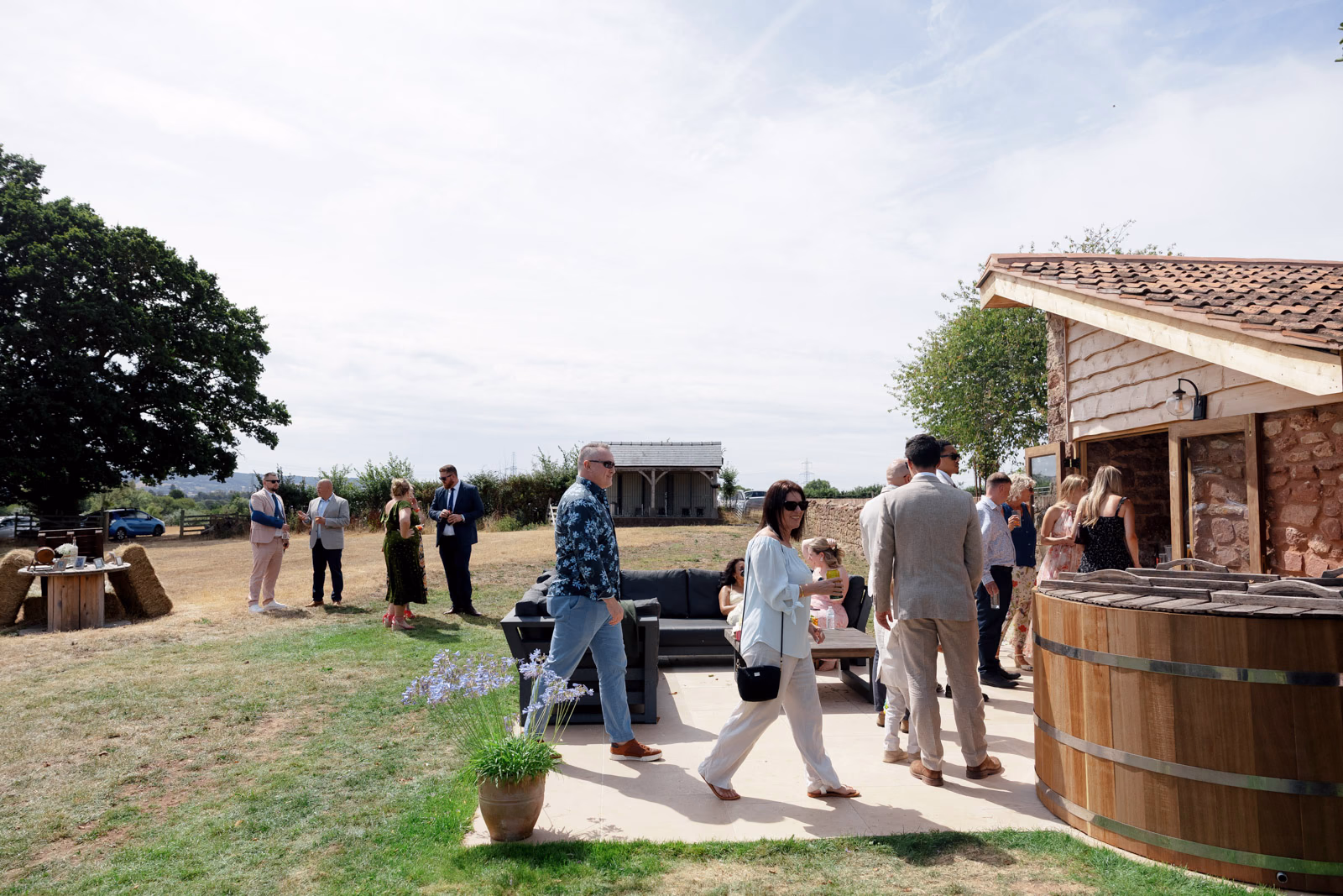 Guests mingling farm outbuildings at a family farm wedding in Taunton