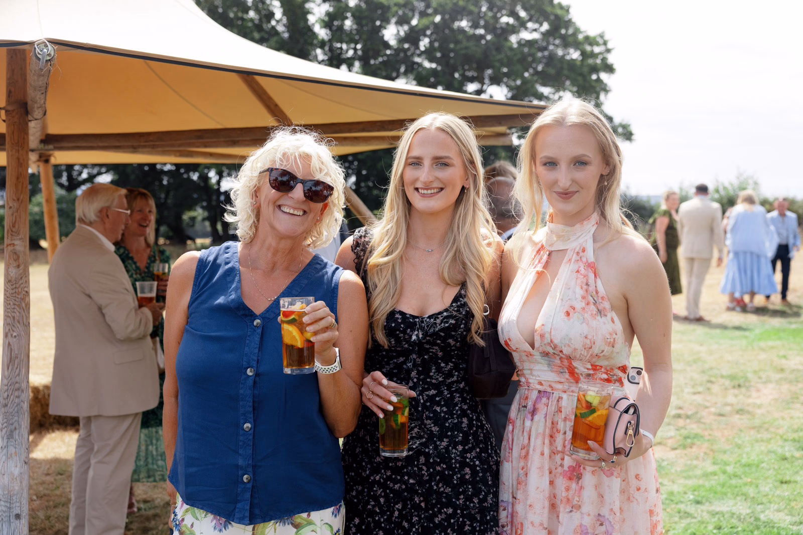 Three guests with drinks summer wedding at a countryside wedding in Taunton, Somerset