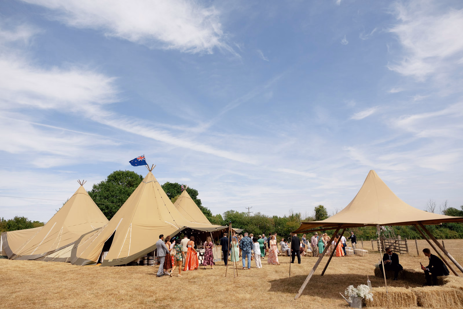 Tipi wedding guests gathering in field at a family farm wedding in Taunton
