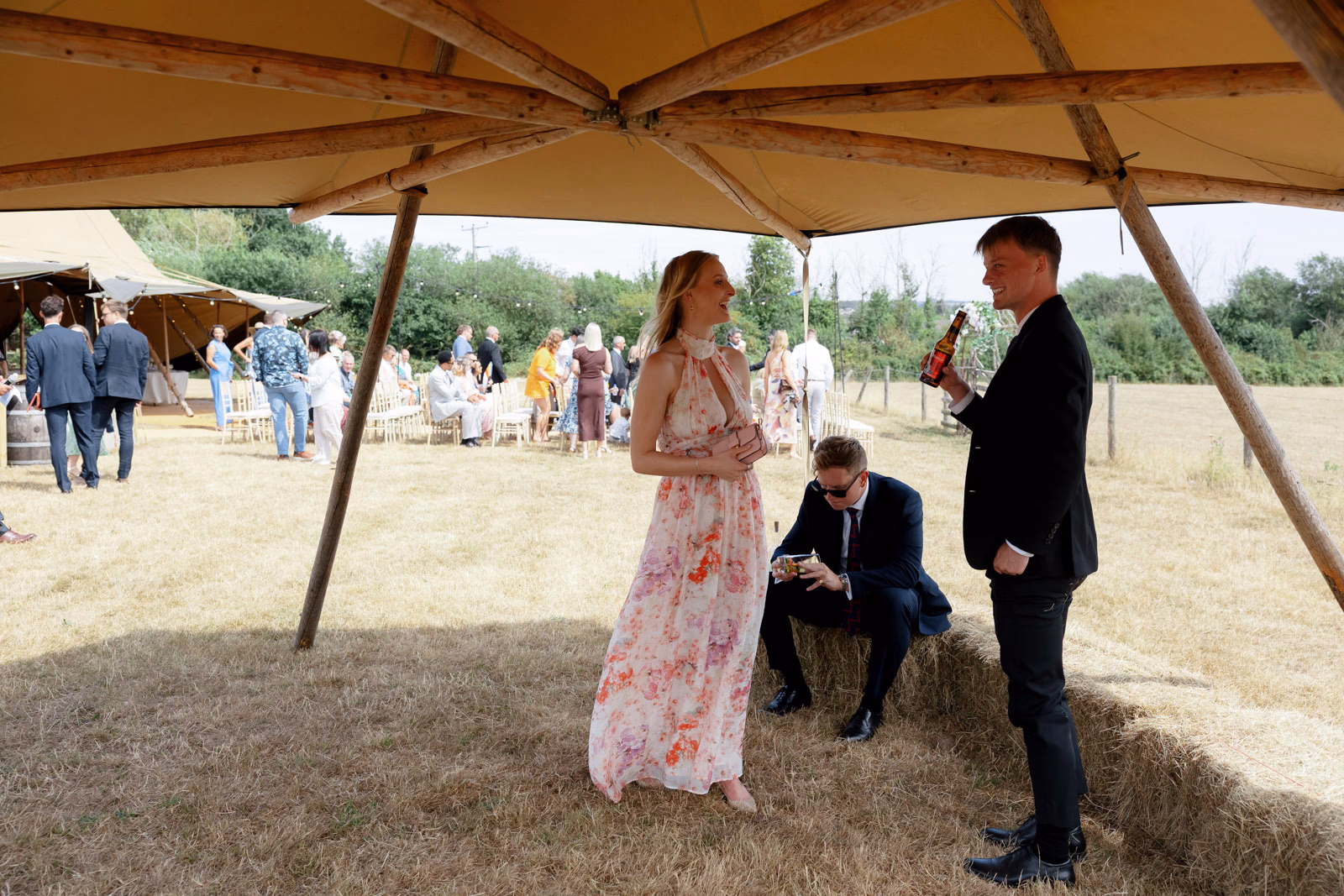 Guests chatting under canopy hay bales at a countryside wedding in Taunton, Somerset
