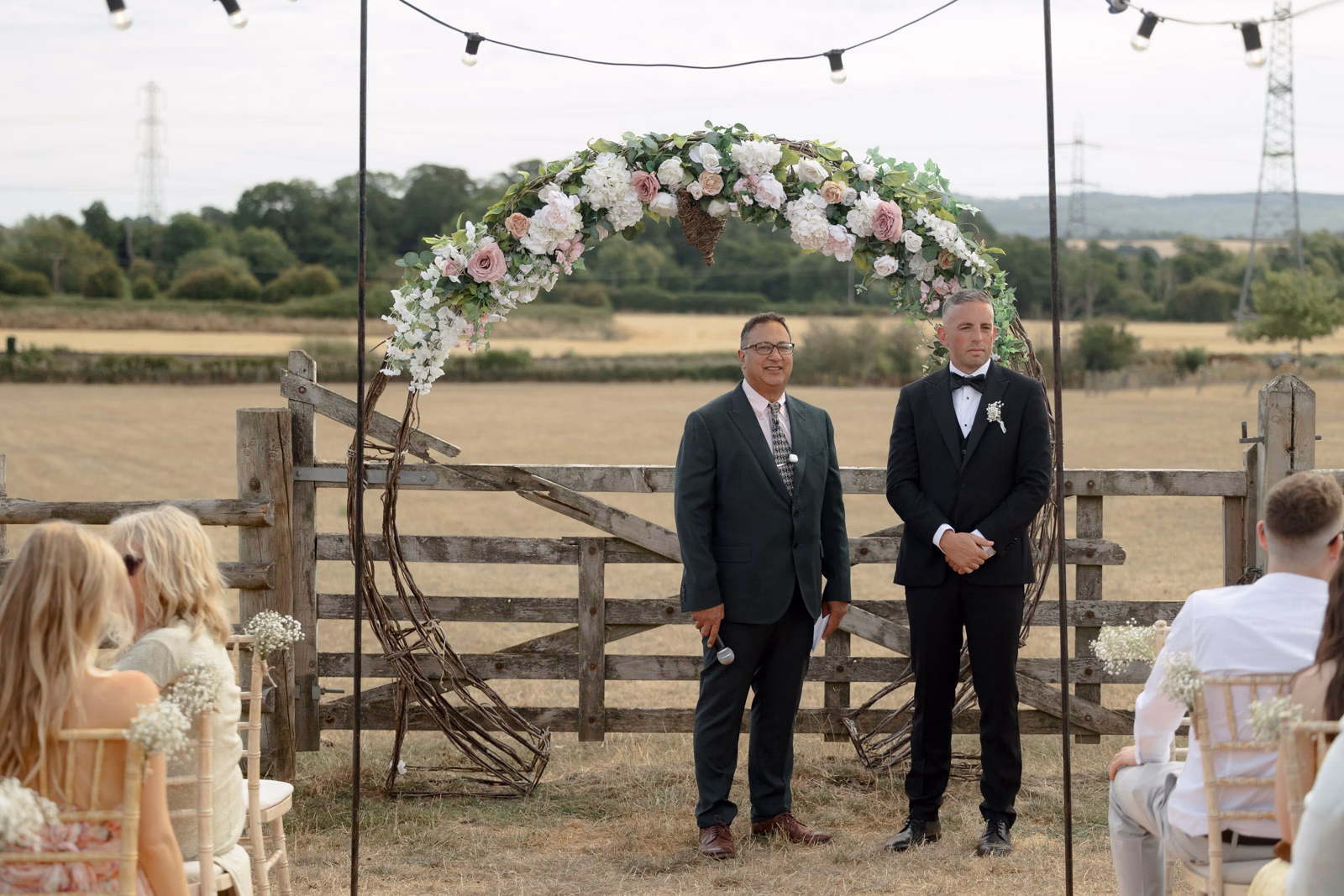 Groom and groomsman waiting at floral arch at a countryside wedding in Taunton, Somerset