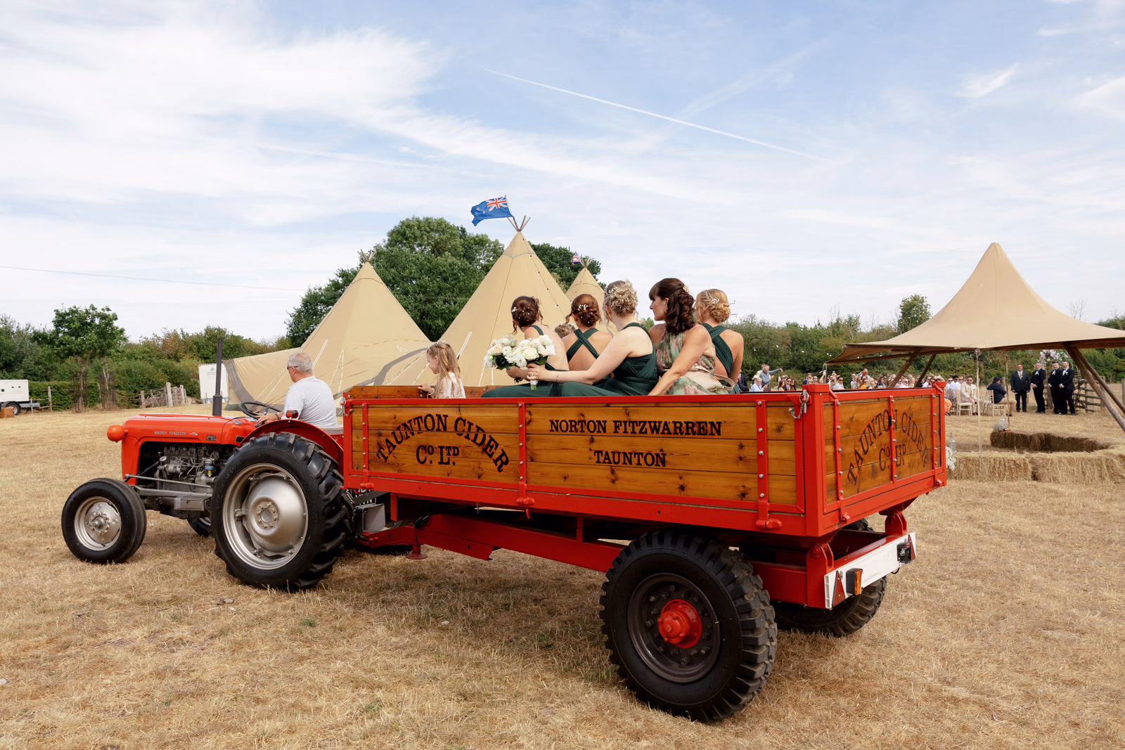 Bridesmaids and guests on tractor trailer at a family farm wedding in Taunton