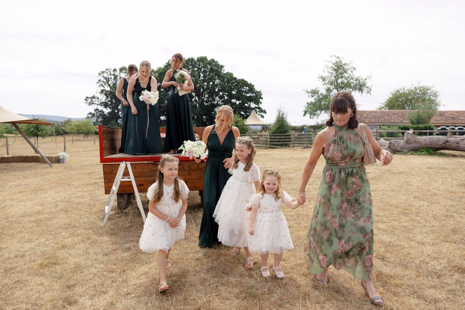 Flower girls and bridesmaids walking from trailer at a family farm wedding in Taunton