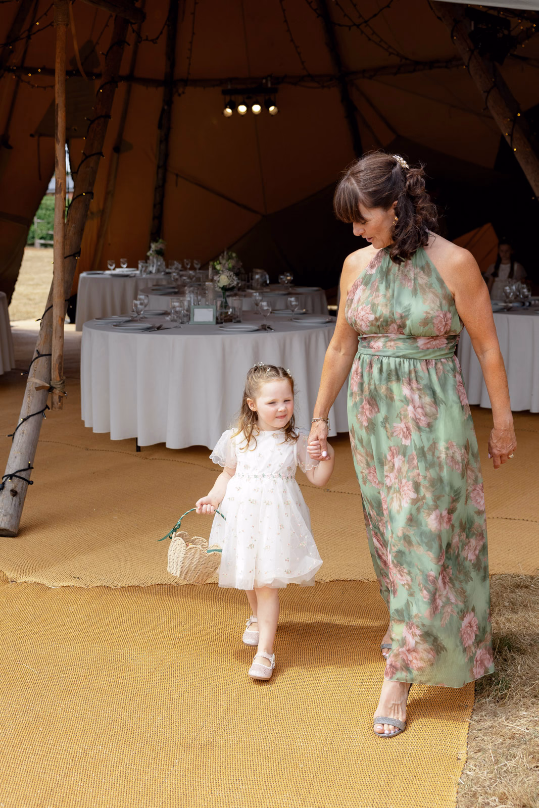 Flower girl walking with guest tipi at a family farm wedding in Taunton