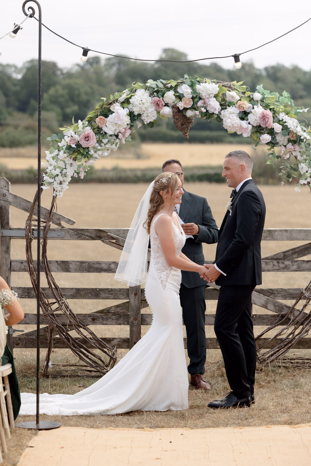 Bride and groom at floral arch ceremony at a Taunton farm wedding, photographed by Tanya Bogdan Photography