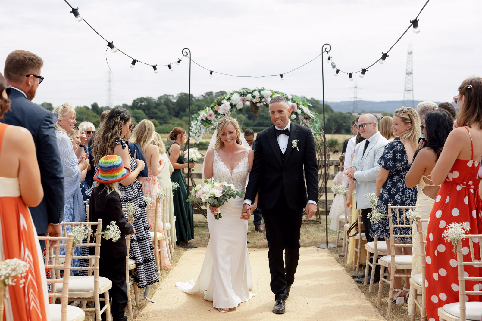Newlyweds walking aisle guests cheering at a Taunton farm wedding, photographed by Tanya Bogdan Photography