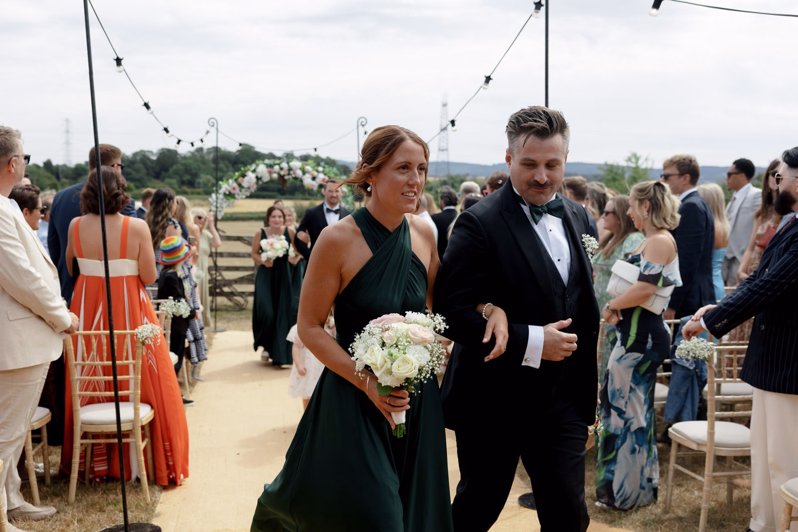 Bridesmaid and groomsman walking aisle after ceremony at a family farm wedding in Taunton