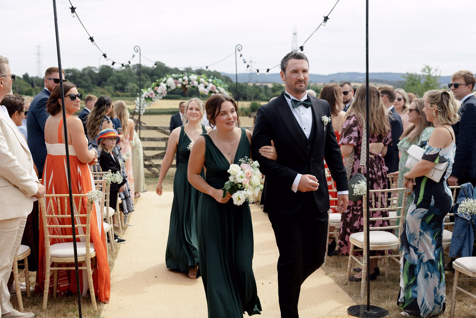 Bridesmaid and groomsman recessional aisle at a Taunton farm wedding, photographed by Tanya Bogdan Photography