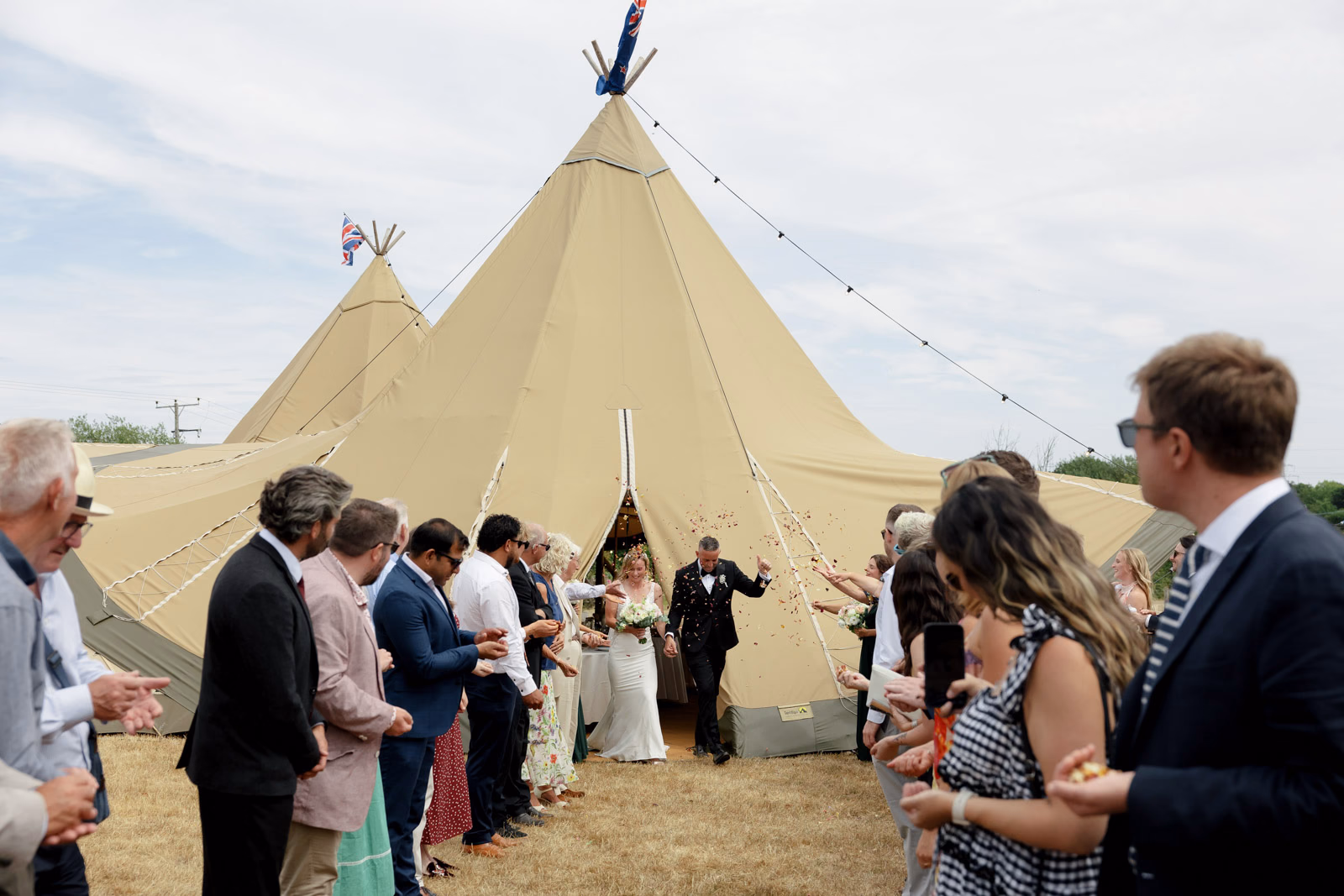 Newlyweds with guests outside tipi at a Taunton farm wedding, photographed by Tanya Bogdan Photography
