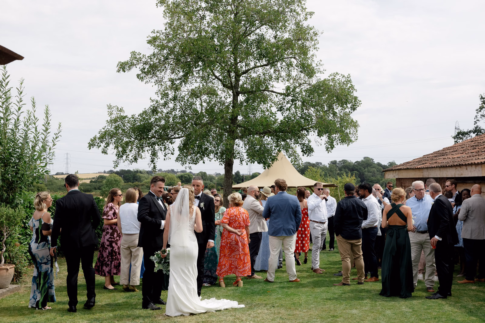 Newlyweds with guests on lawn at a Taunton farm wedding, photographed by Tanya Bogdan Photography