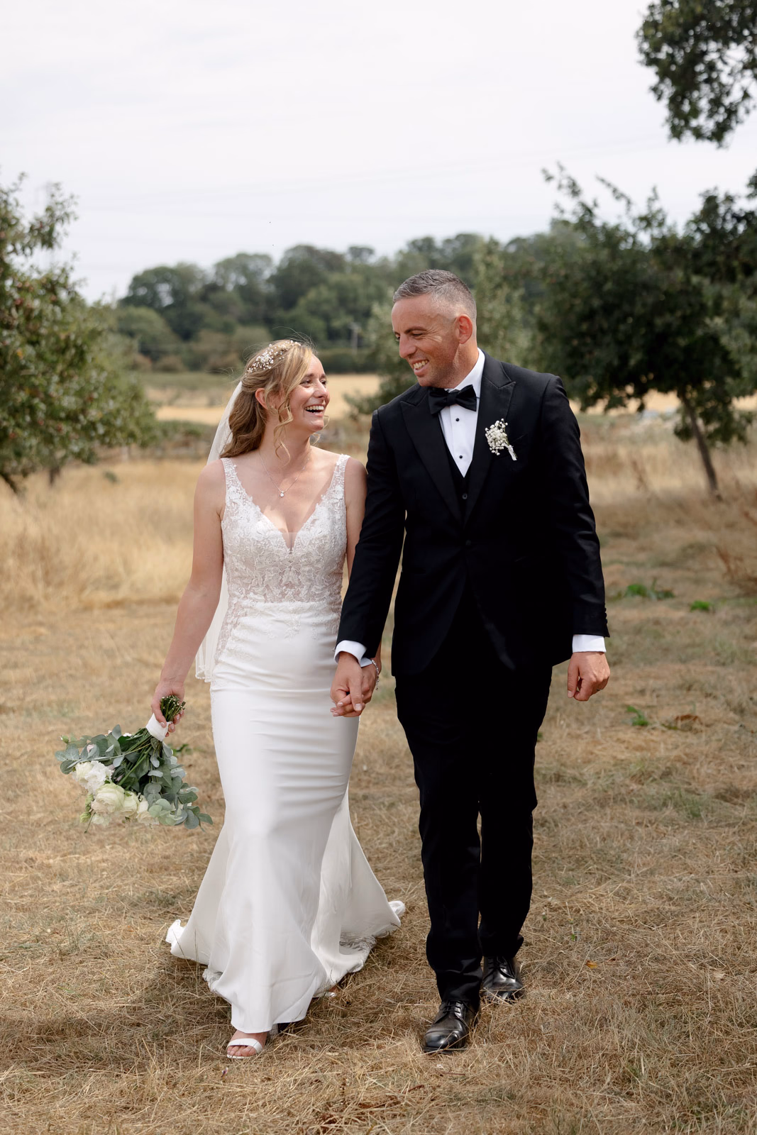 Bride and groom walking orchard at a Taunton farm wedding, photographed by Tanya Bogdan Photography